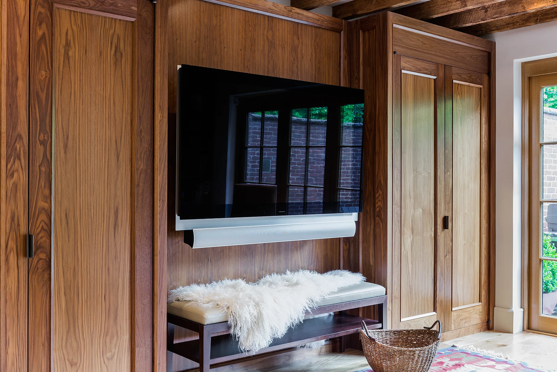 Built in walnut closets and TV wall. Upholstered bench in walnut with leather seat. 