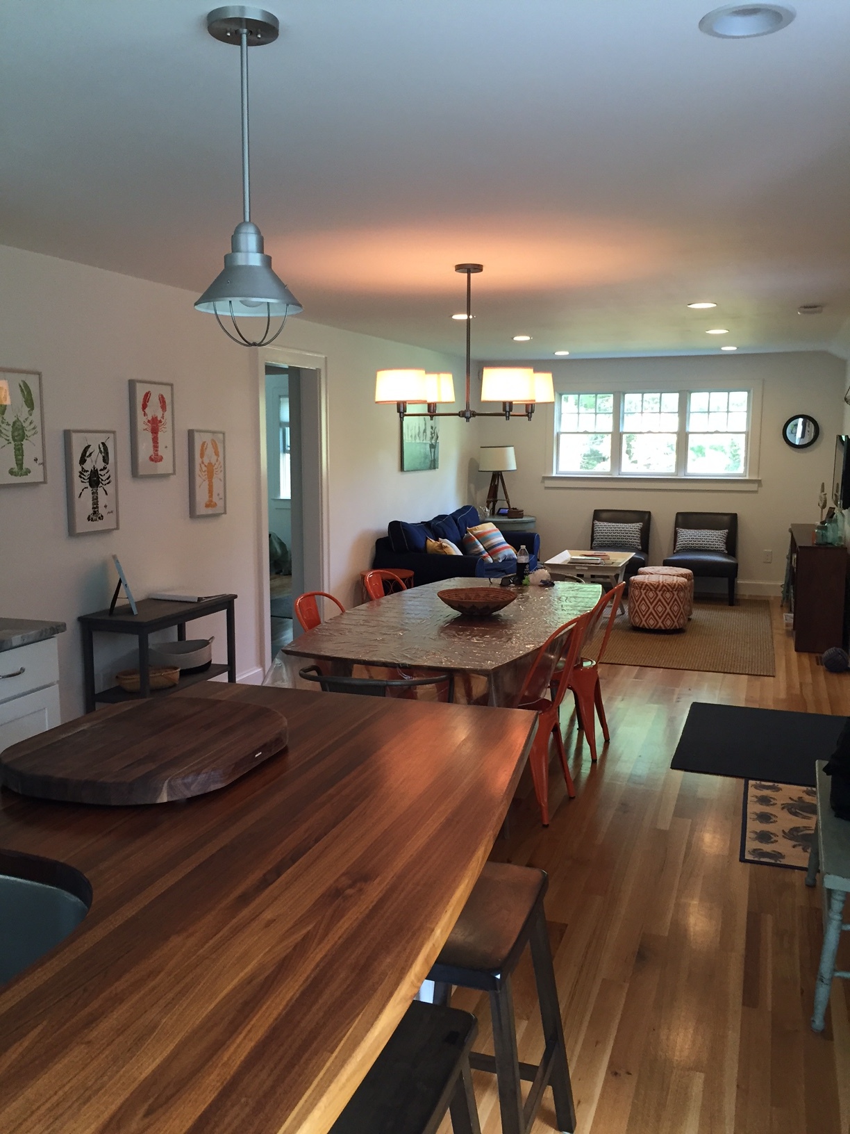 The kitchen, dining and living was open concept. I love the mix of materials and pops of color throughout, especially the orange Marais chairs at the dining room table. The lobster prints on the wall are from a local artist named John Doherty out of Harwich, MA.