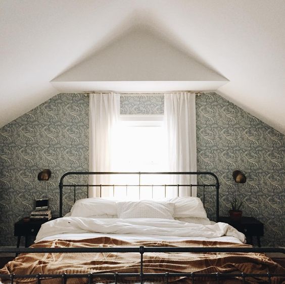 How moody is this bedroom? I love the wallpapered accent wall and how they used sconces vs. table lamps to not overwhelm the area around the bed. Image via A Joyful Journey