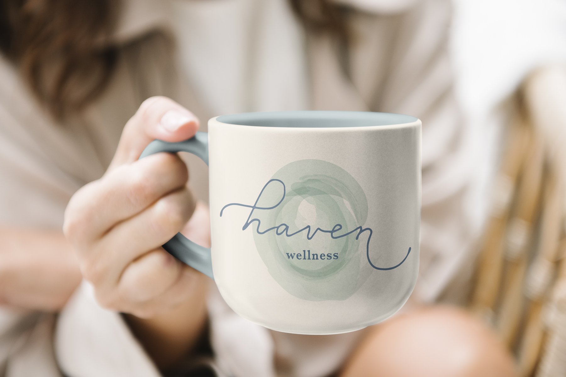  Person holding a blue and white mug with the Haven logo on it 