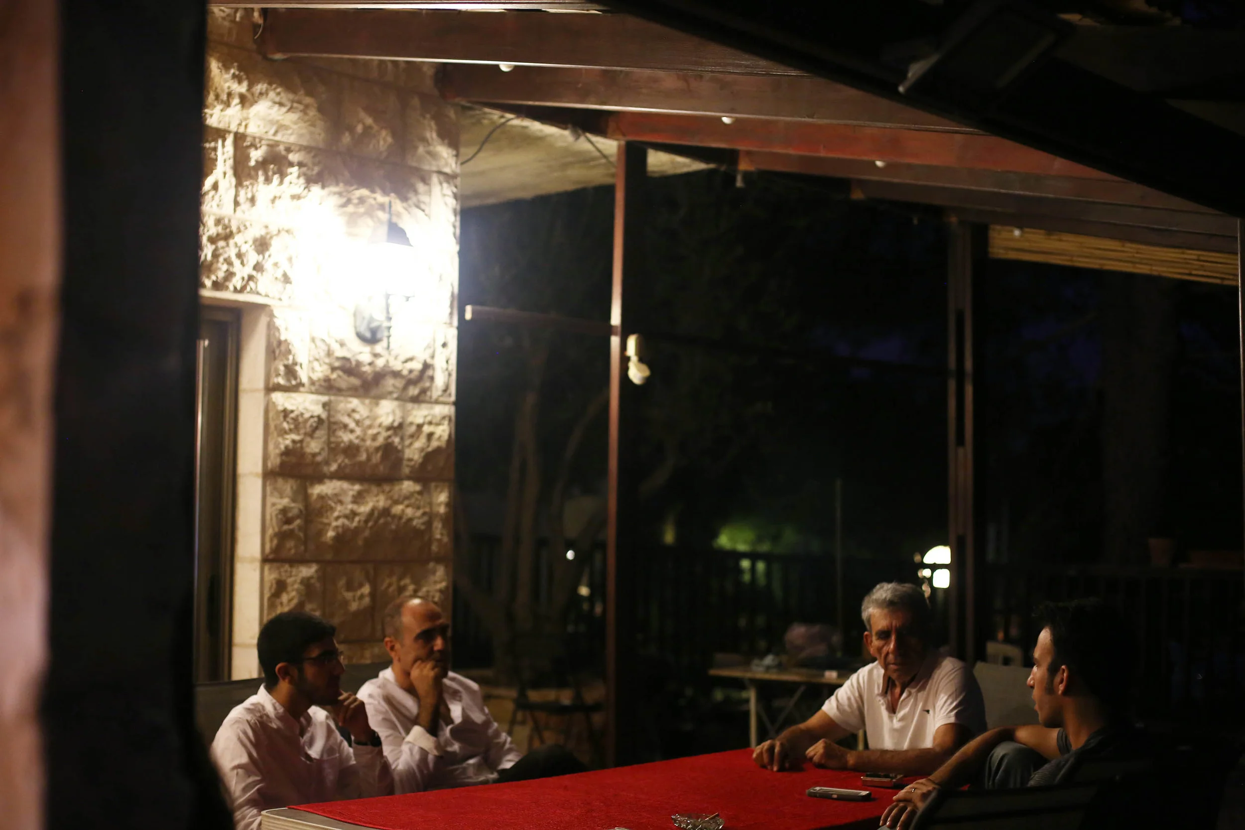 The men sit outside smoking and discussing politics while the table is being set.