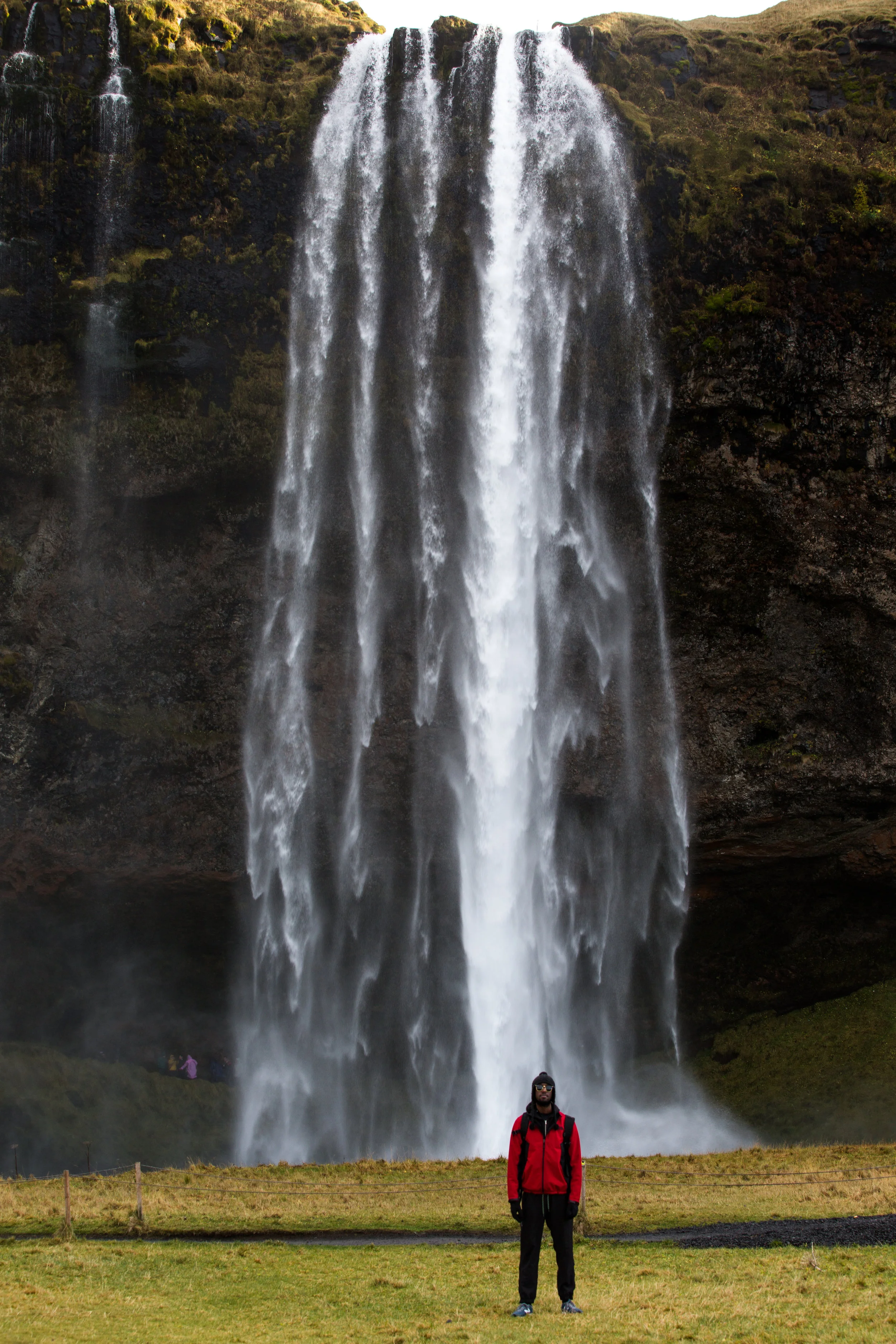 Giants standing among giants. Seljalandsfoss is a 60 meter waterfall that is part of the Sejalands River. Born from the volcanic glacier Eyjafjalla, it's normally know as the waterfall that you can walk behind through a carved mountain wall.