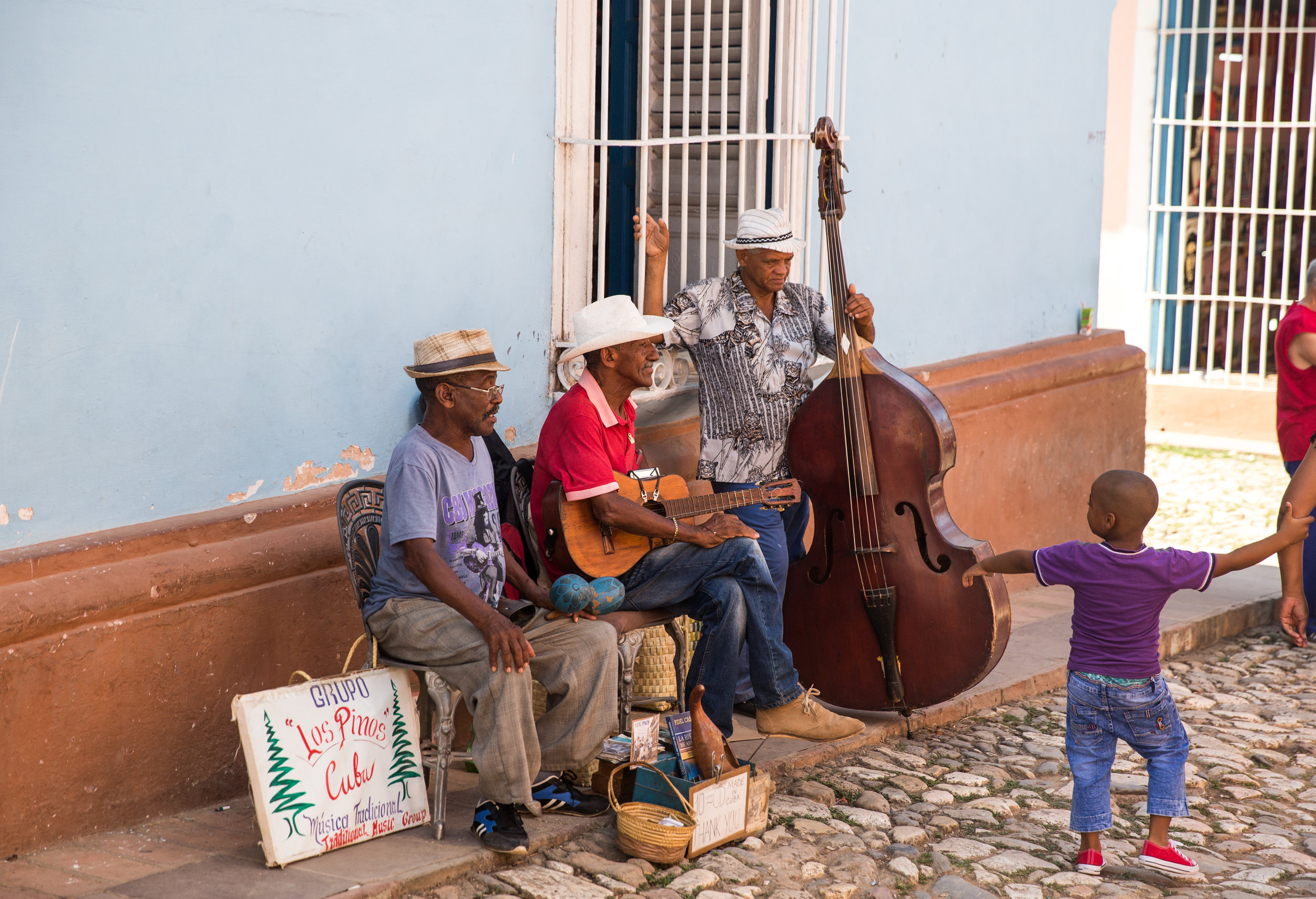 Los Pinos takes a break while a young Cuban boy admires the trio.