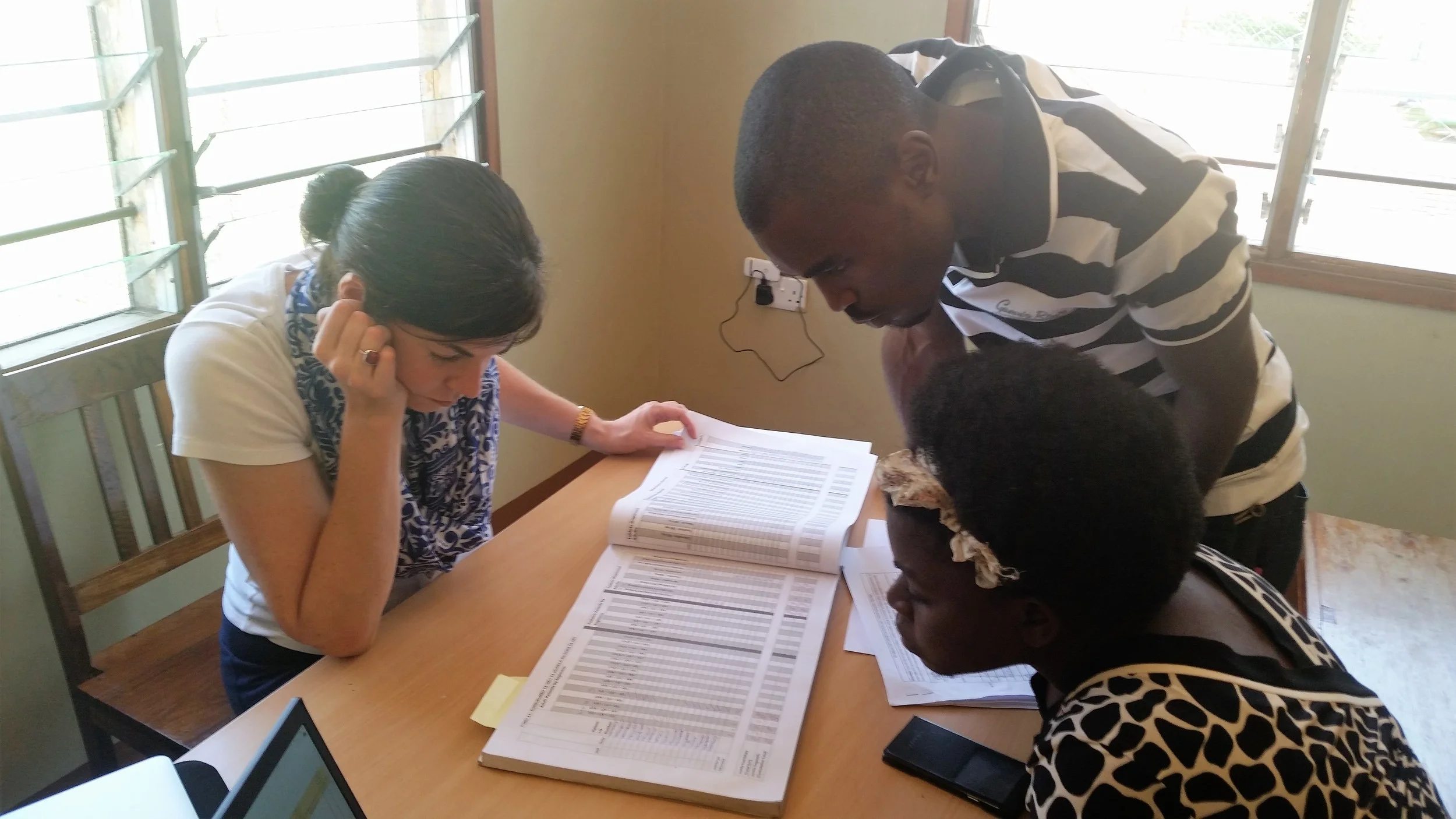 Collecting data about mother-to-child HIV transmission with Research Assistants Agatha and Kassim at Tinde Health Center in Shinyanga Region, Tanzania