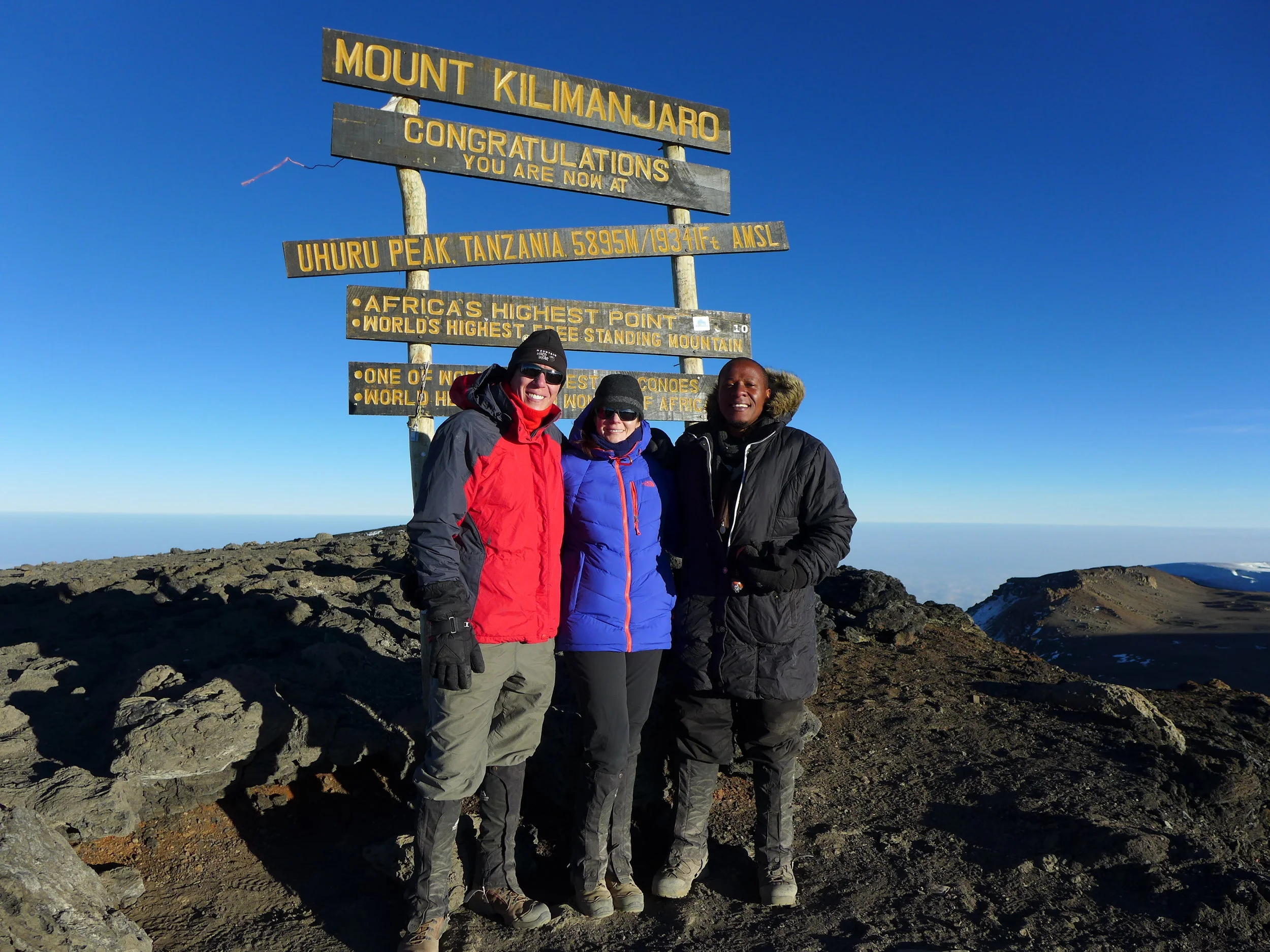 Sandi, her husband Brian Lewis, and long-time collaborator Dr. Prosper Njau at the top of Mount Kilimanjaro.