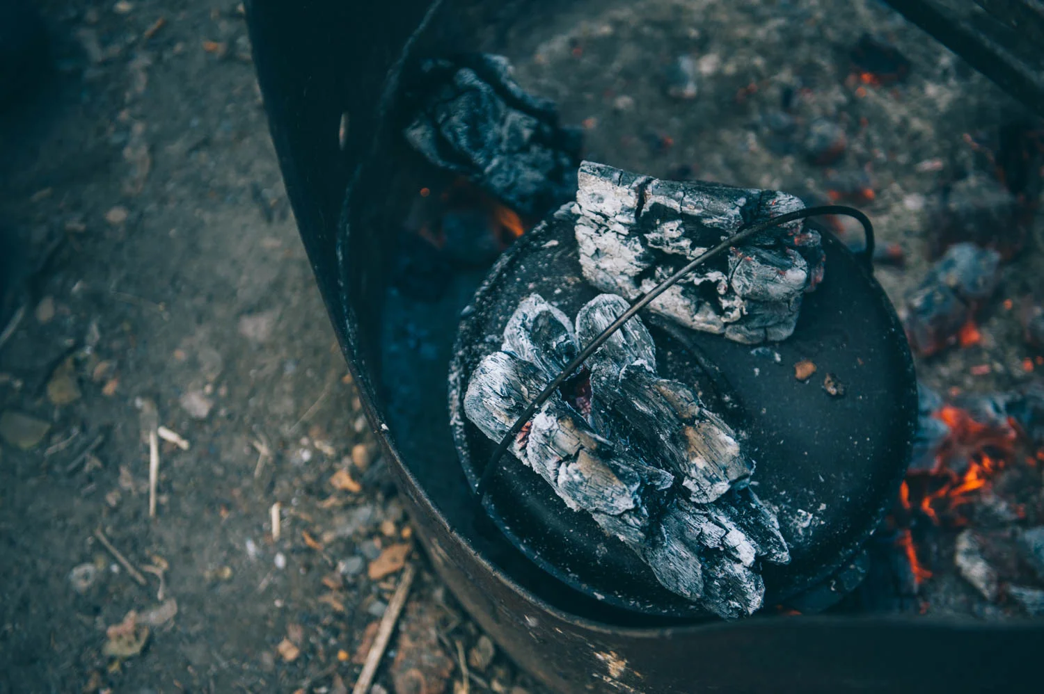 The trick is to have a 3 to 1 ratio of coals (3 on top, 1 at the bottom) and to have the bottom on a trivet or a rack so it is not sitting on the coals.