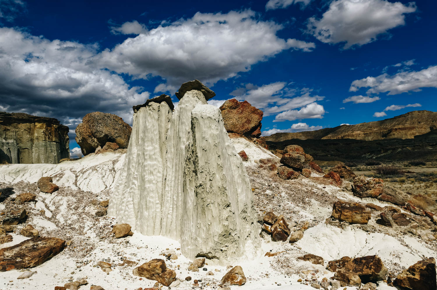 The soft entrada sandstone is pure white in color and forms hoodoos that are often topped either by dark sandstone blocks or unusual boulders of purple conglomerate, composed of small pebbles bonded together.&nbsp;
