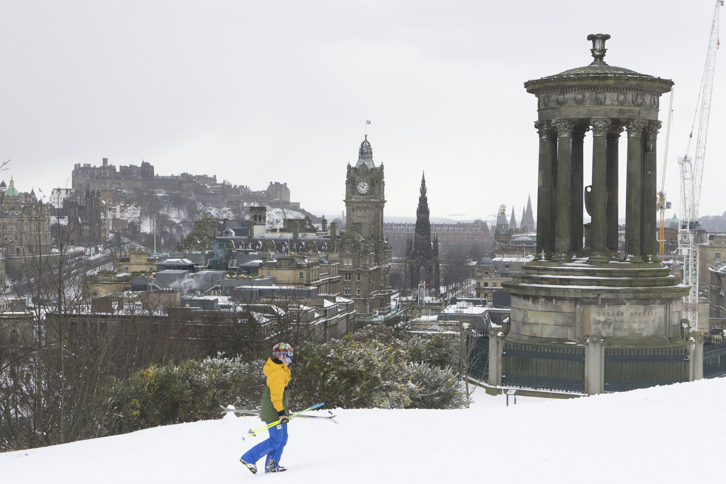  EDINBURGH, SCOTLAND - MARCH 1: A man with skis walks up Calton Hill which overlooks the city centre following heavy snowfall on March 1, 2018 in Edinburgh, United Kingdom. People have been warned not to make unnecessary journeys as the Met office is