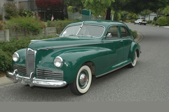 Here is a full portrait of the Packard. We drove it on several local tours with the NorCal Packard Club, but Roy wanted to add an overdrive transmission and sent it to a shop in Napa, CA, that specializes in Packard restorations. It’s an old joke among Packard owners who send their cars to be fixed that one thing leads to another. The owner of the shop loves his work and wants to send a perfect car back to its owner. In our case, he found that the electrical system needed to be replaced, so we ordered a new wire harness. The dashboard was a bit beat up, so we had it redone in Modesto, CA. We’ve seen it—all beautifully rewooded—and it’s a thing of beauty. As time has passed, all light sockets have been taken out, sandblasted, and repainted. The gas tank has been redone. We visit it sometimes and it’s coming along. When it finally reaches a state that the shop owner considers satisfactory, we will have to find garage space for it, so we’re not pushing too hard. Then in 2006 he acquired a rather rare 1940 Mercury Tudor. (That’s not a period in English history, but Ford’s name for two-door.) We also know this car’s history. It was originally purchased by a man in South Dakota in December 1939. It was only the second year the Mercury was in production, and it was an impressive car to own in his small town. He went to war and put it up on blocks in the barn before he left. Like many other young men, he didn’t come home. In 1947 the neighbors talked the widow into selling them the car. They took excellent care of it and it was used as a backdrop on their Christmas cards. The wife said she never had to worry about the kids getting into trouble because when they drove the Merc, everybody in town knew the car and would report on them. By 1980 the kids were grown and gone and she put the car up for sale. It was purchased by a man in Arastridaro. He did what’s called a “complete body-off,” meaning the body was taken off the frame. He installed a late-model Mustang motor, automatic transmission, late-model rear end, and independent front suspension with disk brakes. When the body was put back it was repainted a deep navy blue with subtle ghost flaming on the front end, and featuring blue with red accents on the hubcaps. He reupholstered the interior and trunk interior to restore the original look. The result was a rather elegant hot rod that he entered in car shows. In 2004 he sold the car to a friend of ours in the Packard Club. When our friend bought yet another car, his wife said he had a sell one. He knew Roy loved the Mercury so he called him and a deal was made. He now wants it back, but it’s our baby and that’s not going to happen.