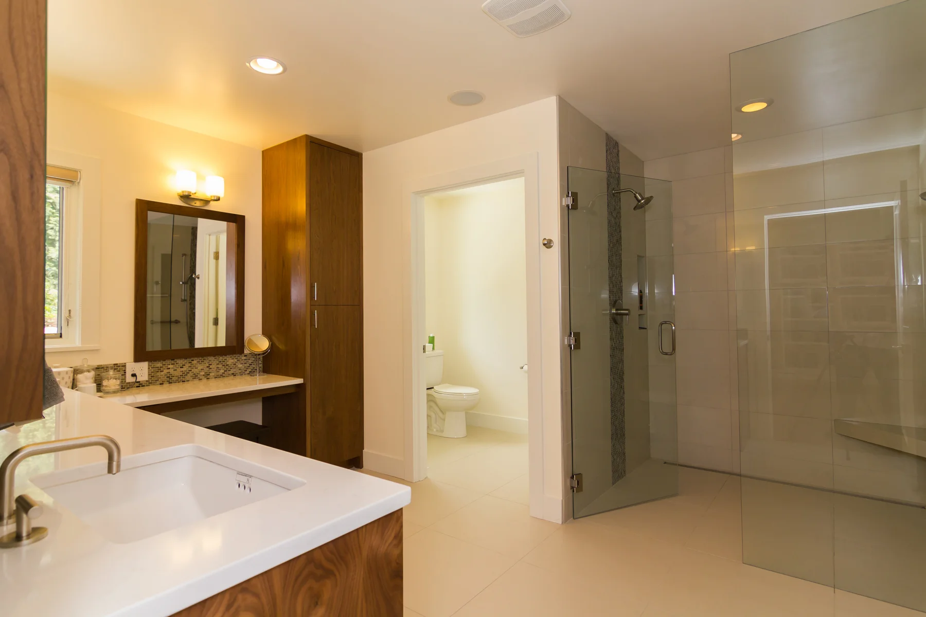 New master bathroom with no-threshold glass shower enclosure, heated stone floors, vanity station, and custom walnut cabinets