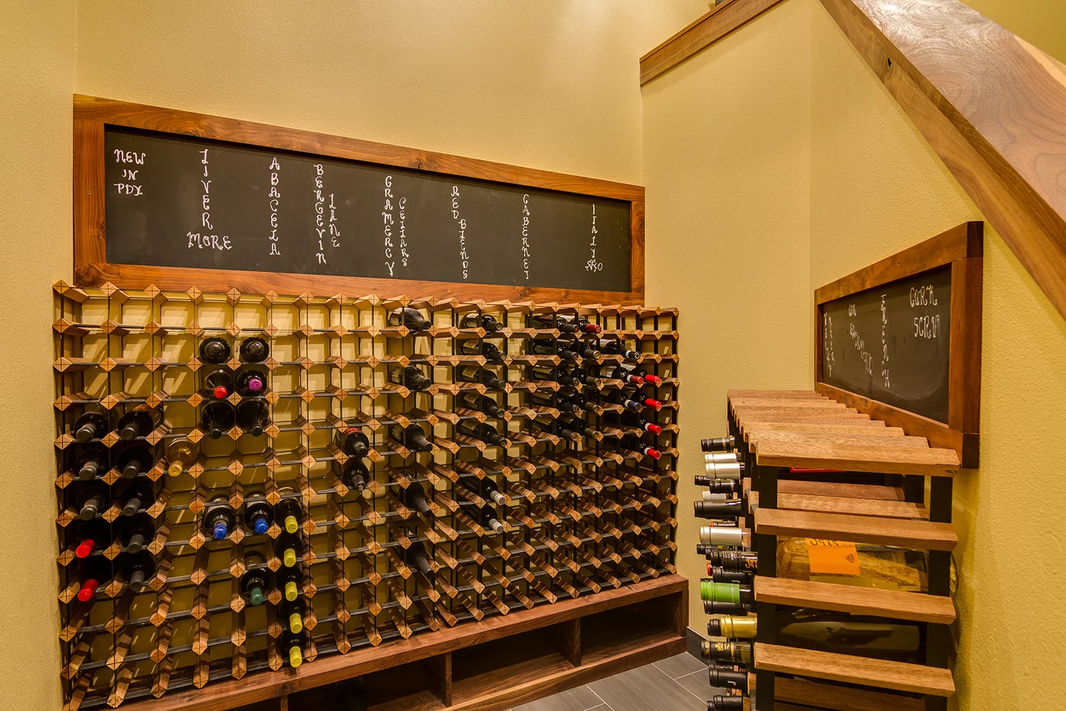 Dark, carpeted closet -----> open wine room at the base of the stairs. Took the stairway wall down to a halfway to bring in more light. Wine racks and custom walnut-framed chalkboards tie in with the stairway trim. New tile and a fresh coat of paint.