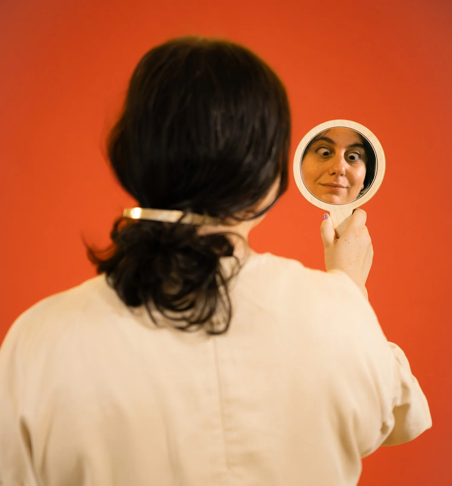 amelia giller looks in a mirror and makes her eyes crossed red background