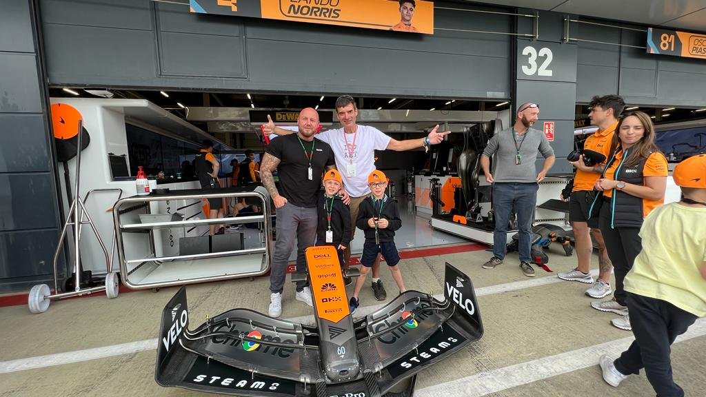 Shropshire Dad Dan Perks with twin sons Ollie and Charlie with STEAM Co. branded McLaren F1 car nose cone and STEAM Co's Nick Corston in the McLaren pits at Silverstone.jpeg