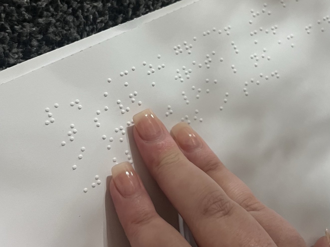 Emily's hand on braille song sheet