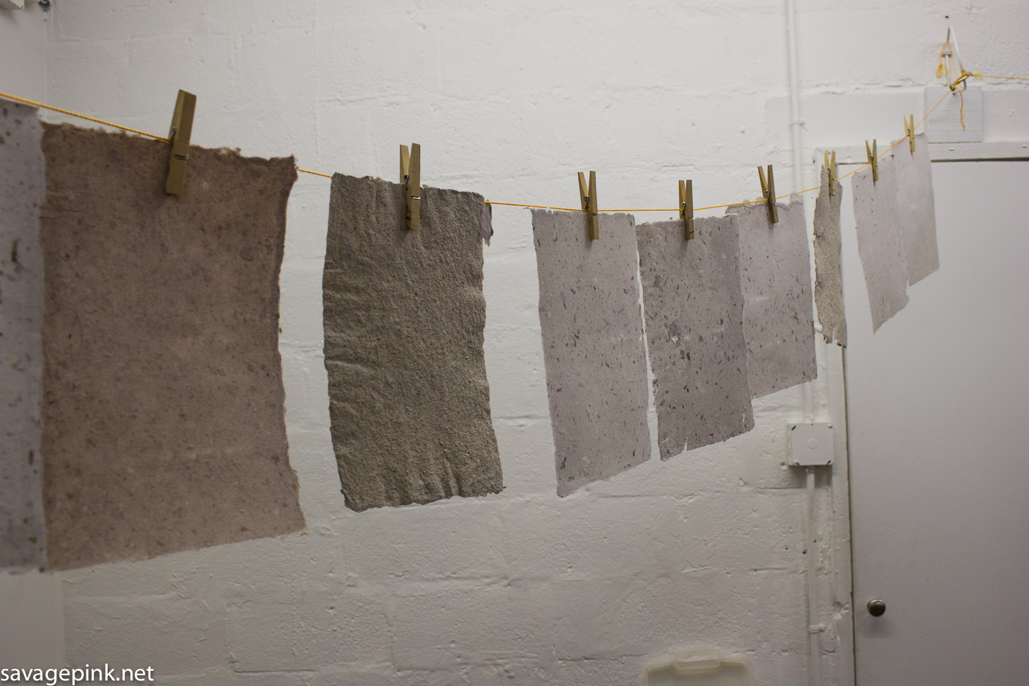 Paper sheets created by visitors, drying on a line.