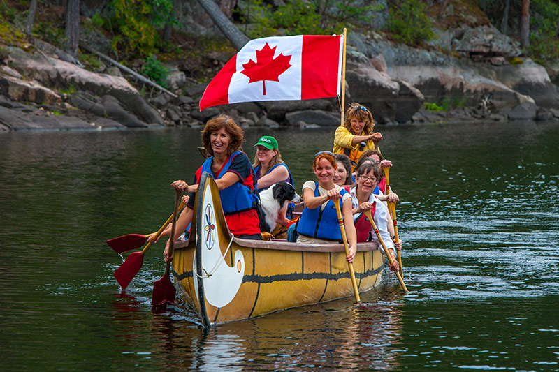 Joanie and Gary McGuffin Joanie assuming the position of ‘Gouvernail’ in a Voyageur Canoe, paddling down the French River between Lake Nipissing and Georgian Bay, Ontario. Photo: ©Gary McGuffin / www.themcguffins.ca