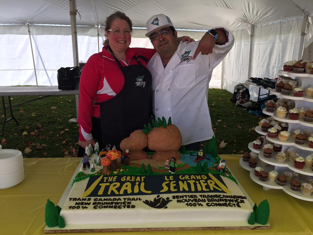 Monkeycakes’ Jonathan and Natalie Ramirez posing with The Great Trail cake