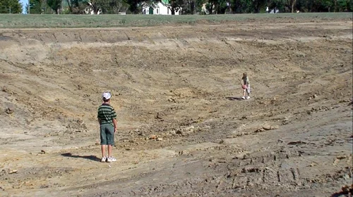 Boys playing football at the bottom of the main dam after a cleanout with an excavator.
