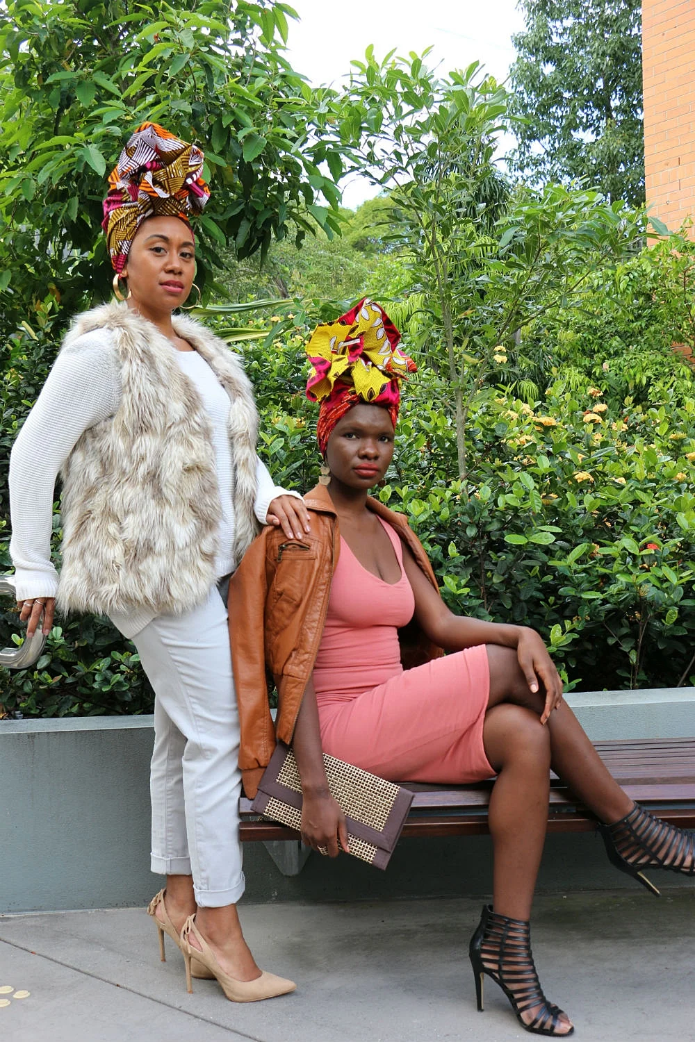 Brand ambassador GRACEY B (standing) teamed her cream cargo pants with a faux fur nude sleeveless jacket, cream loose-fitting jumper and nude heels to highlight the colour palette in headwrap SHERRI. ISATA T is seated beside GRACEY B wearing headwrap TAMARA.