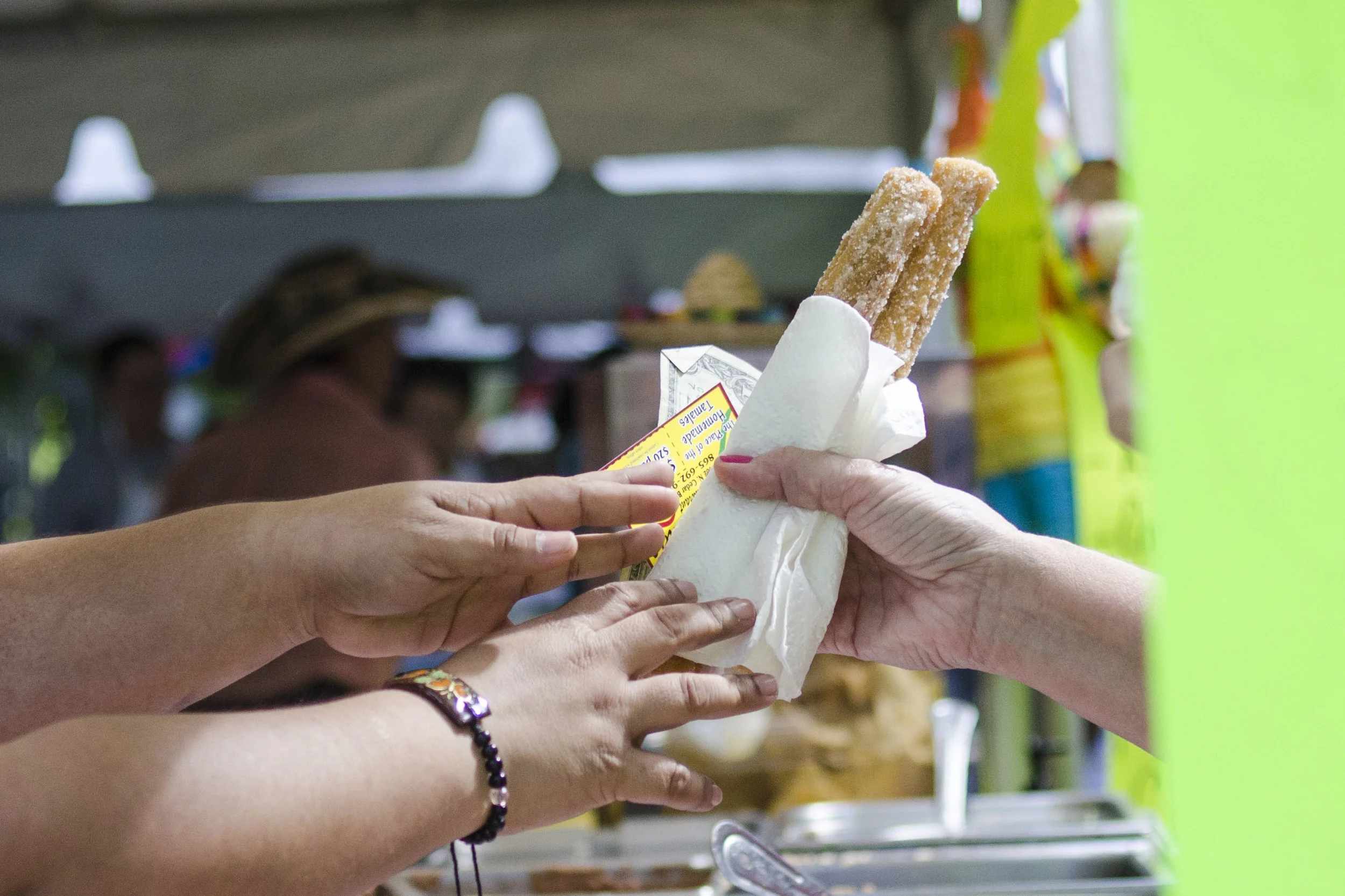 Dozens of tents set up in Krutch Park sell traditional foods of Spanish-speaking countries. In this photo, Katrina Kent exchanges a couple of churros, change, and a business card for her family's Mexican restaurant. 