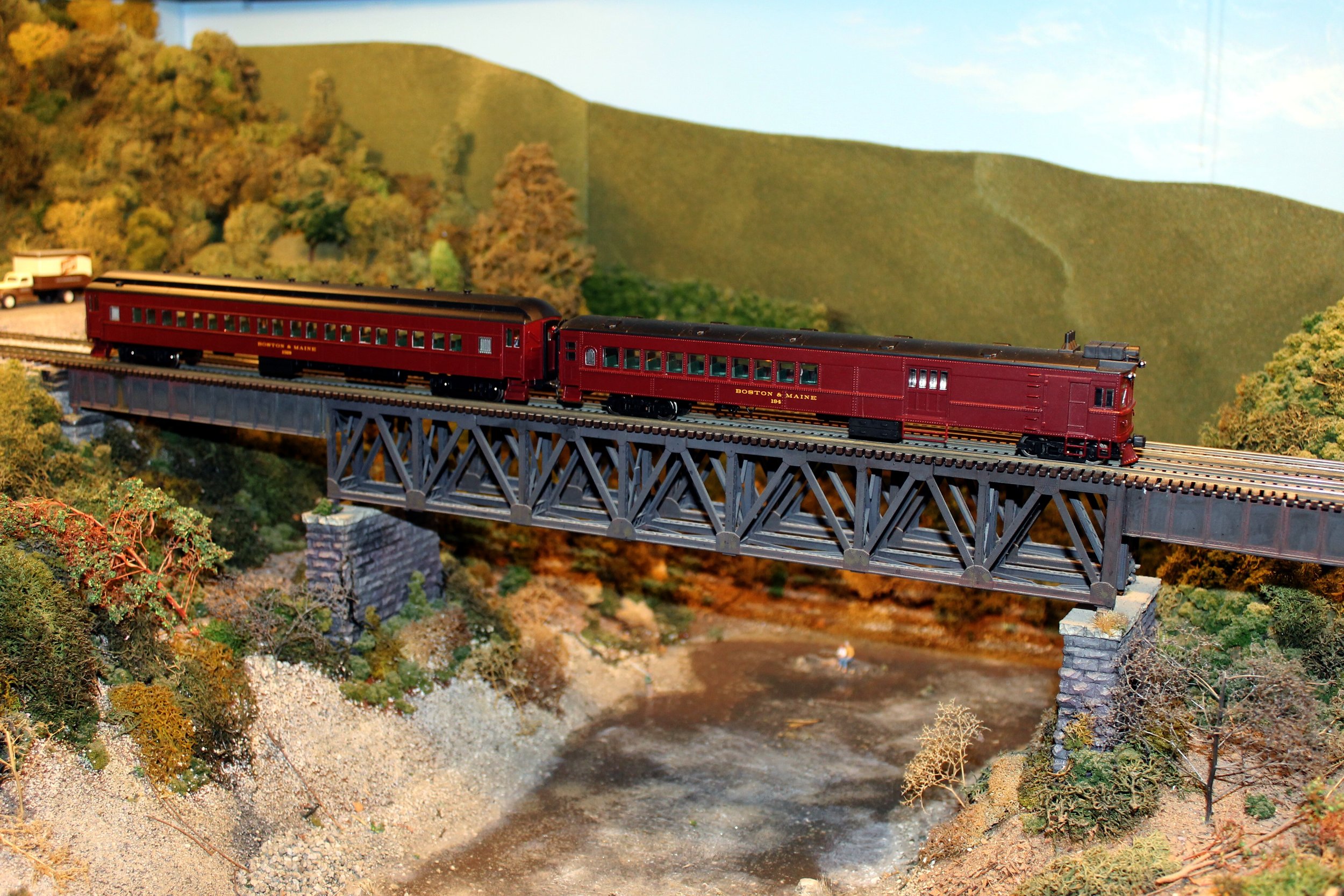 Boston and Maine doodlebug and trailer cross a typical Fitchburg Division deck truss bridge on the Nashua Valley Railroad Association layout in Shirley, Mass. Sept. 17, 2016. Mal Sockol photo.