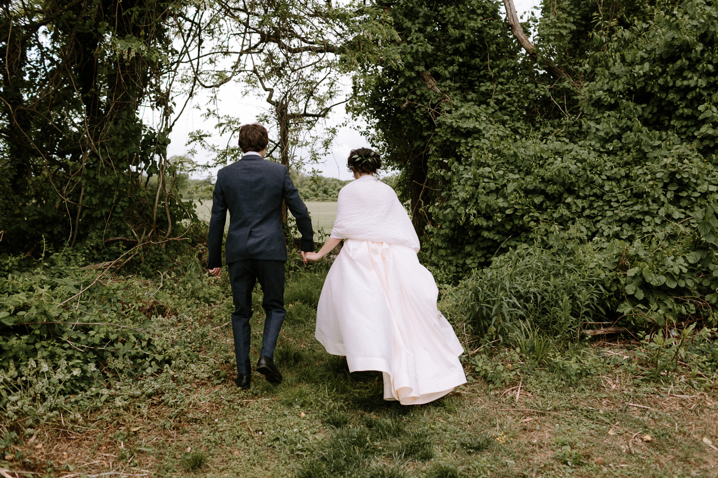 Bride and groom walking into forest