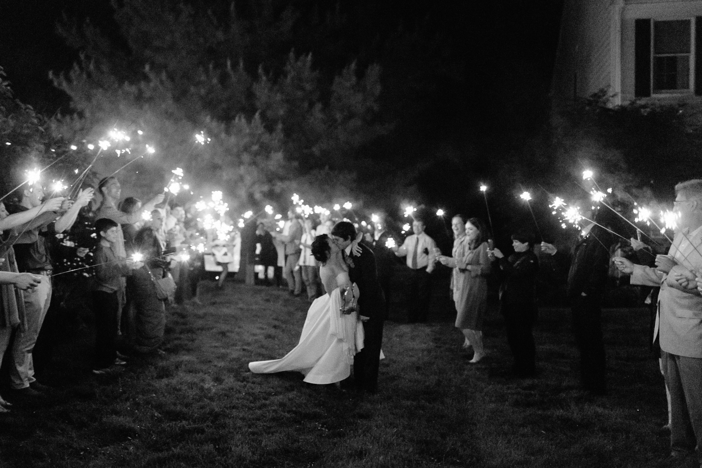 Bride and groom kissing sparkler sendoff