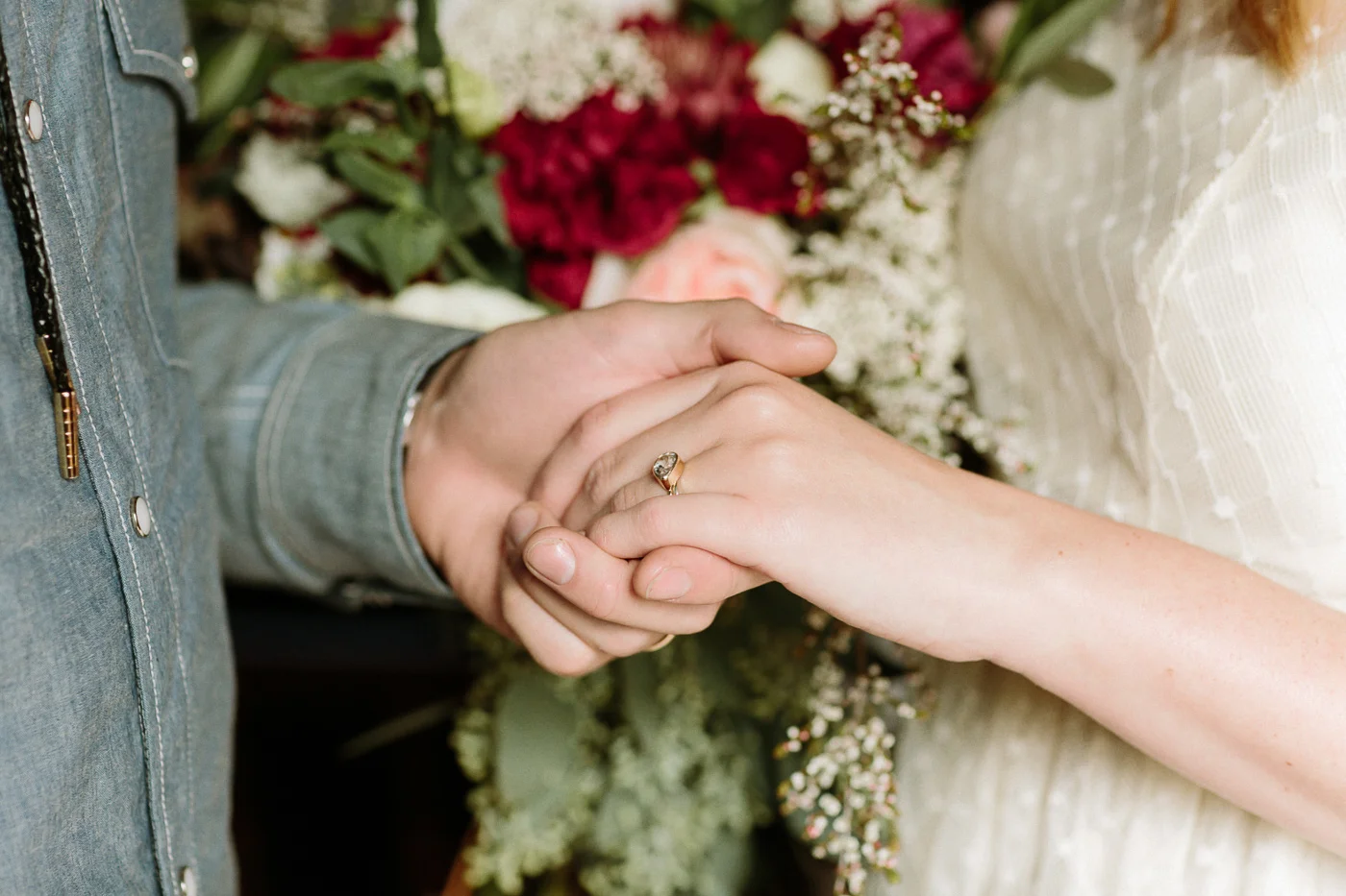 Bride and groom holding hands ring flowers