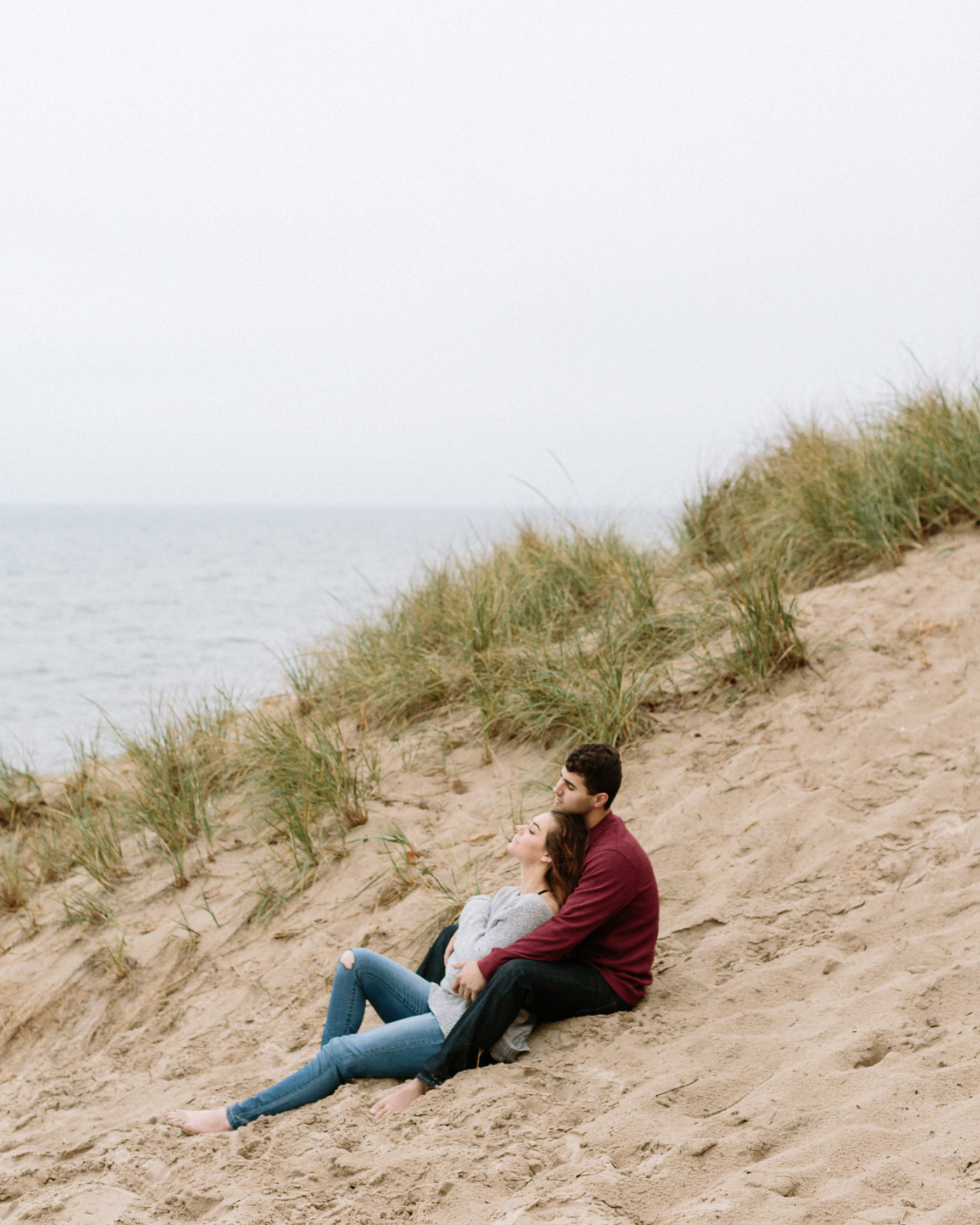 Couple sitting in sand beside Lake Michigan