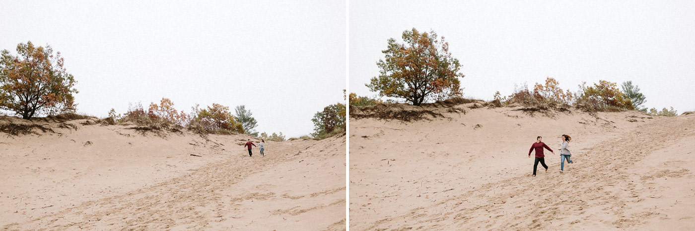 Couple running down dunes