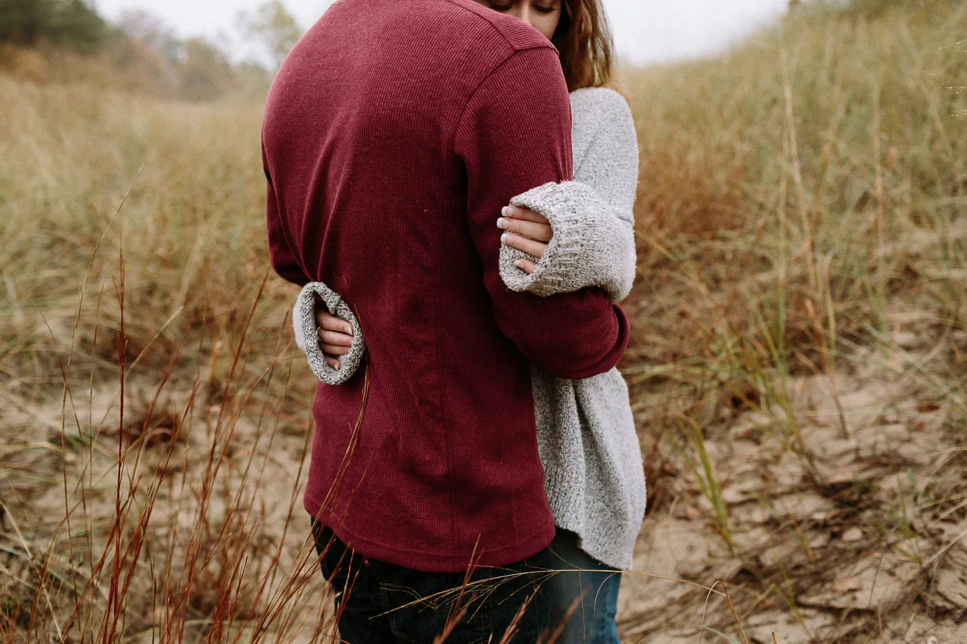 Girl's hands hugging guy at the beach