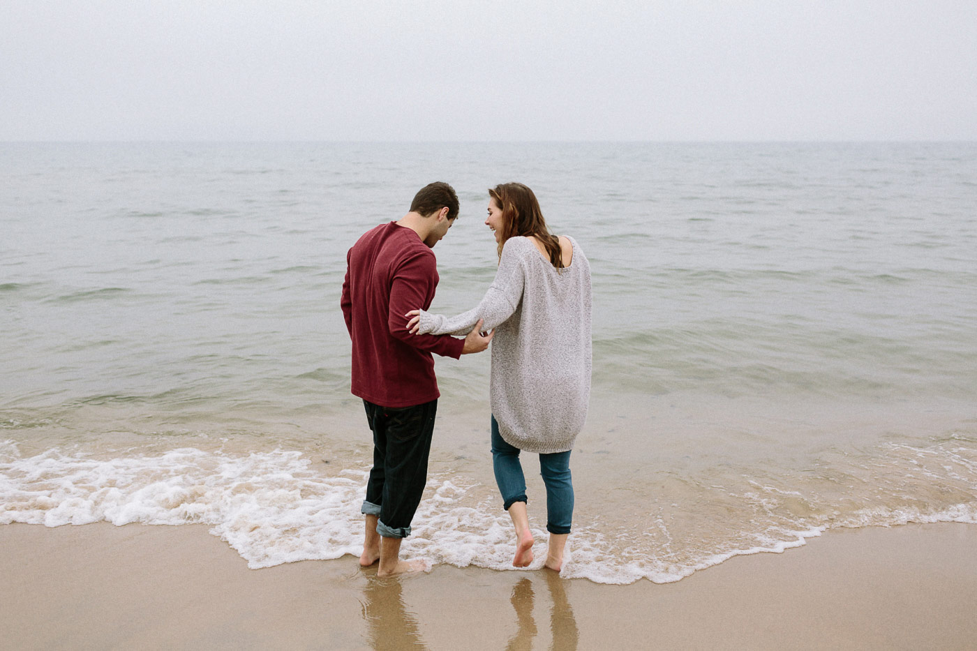 Couple laughing stepping into Lake Michigan