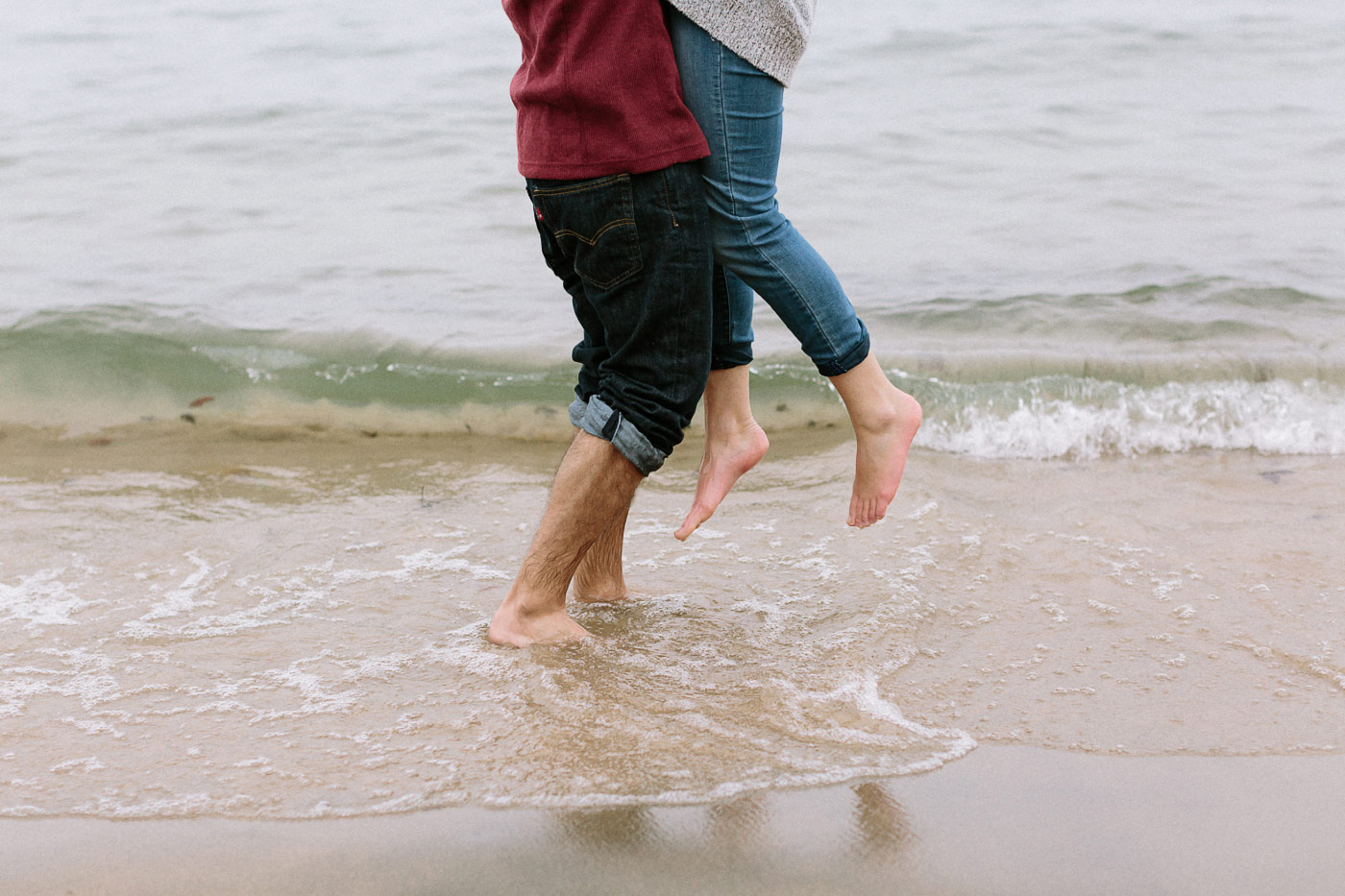 Close up of feet couple hugging in the surf