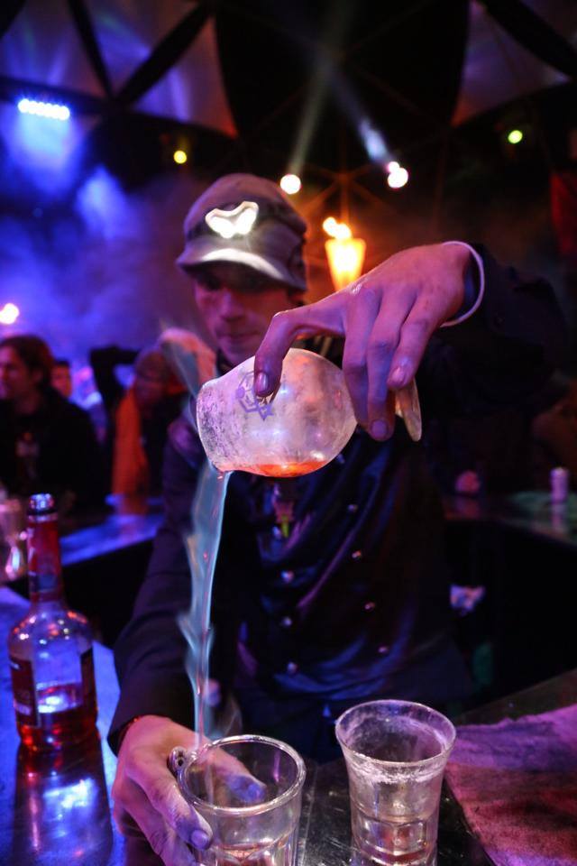 One of Incendia's bartenders pours a flaming shot as onlookers marvel.