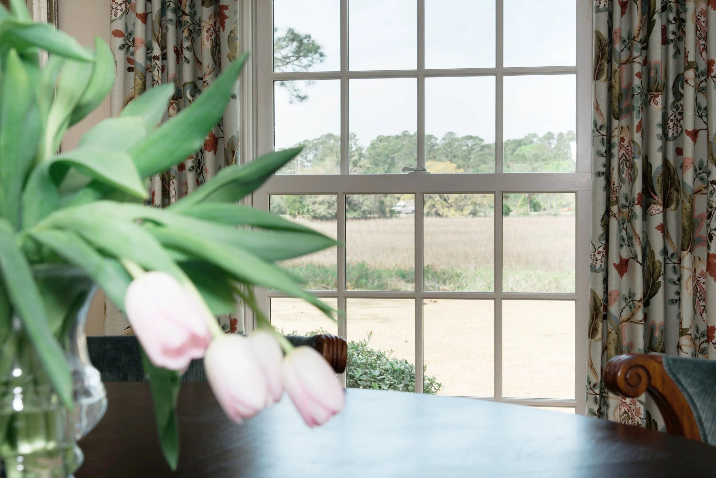 The dining room view overlooking the marsh inspired much of the home's color palette, with rich hues of blue, green, and soft cream. Drapery Fabric: Schumacher