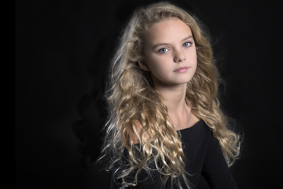 Kleur foto van tiener meisje met krullend blond haar genomen in de fotostudio in Loosdrecht met windmachine.jpg