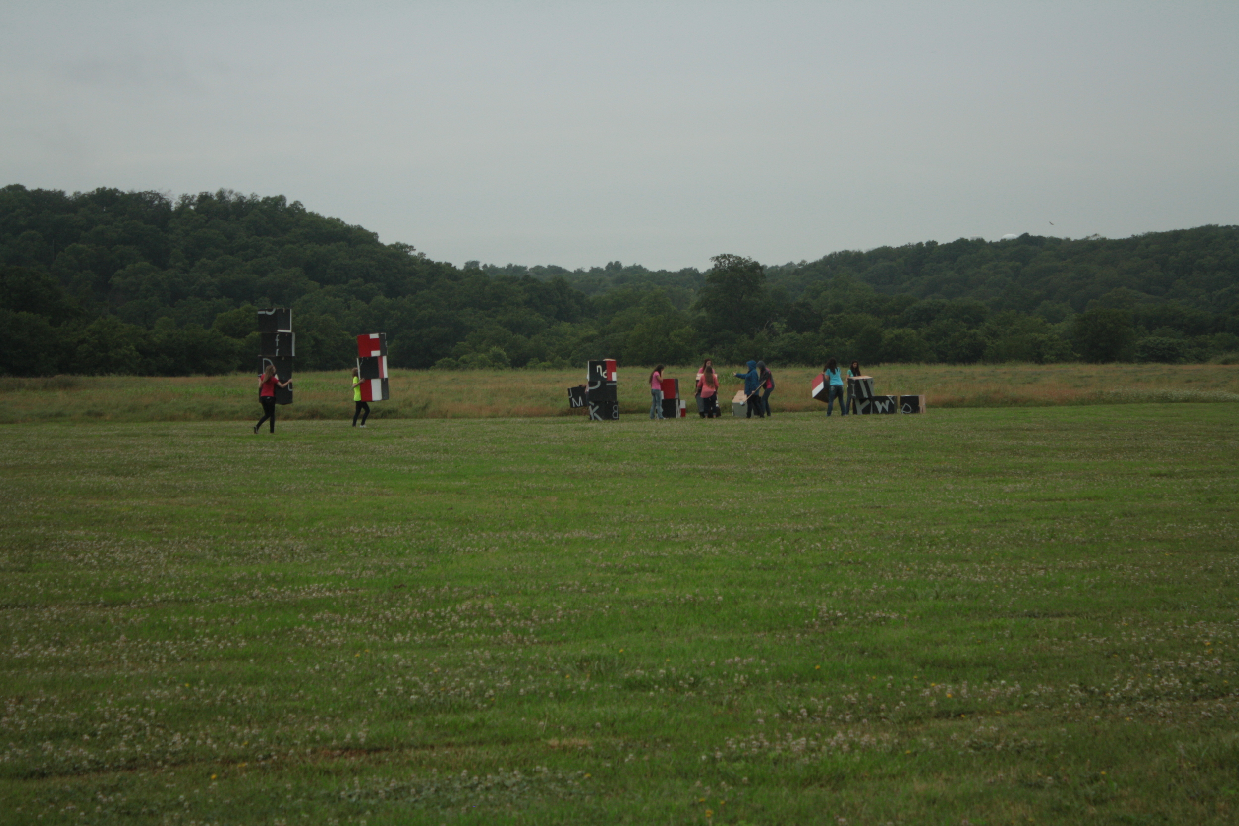 The students carrying their boxes to the middle of the field.