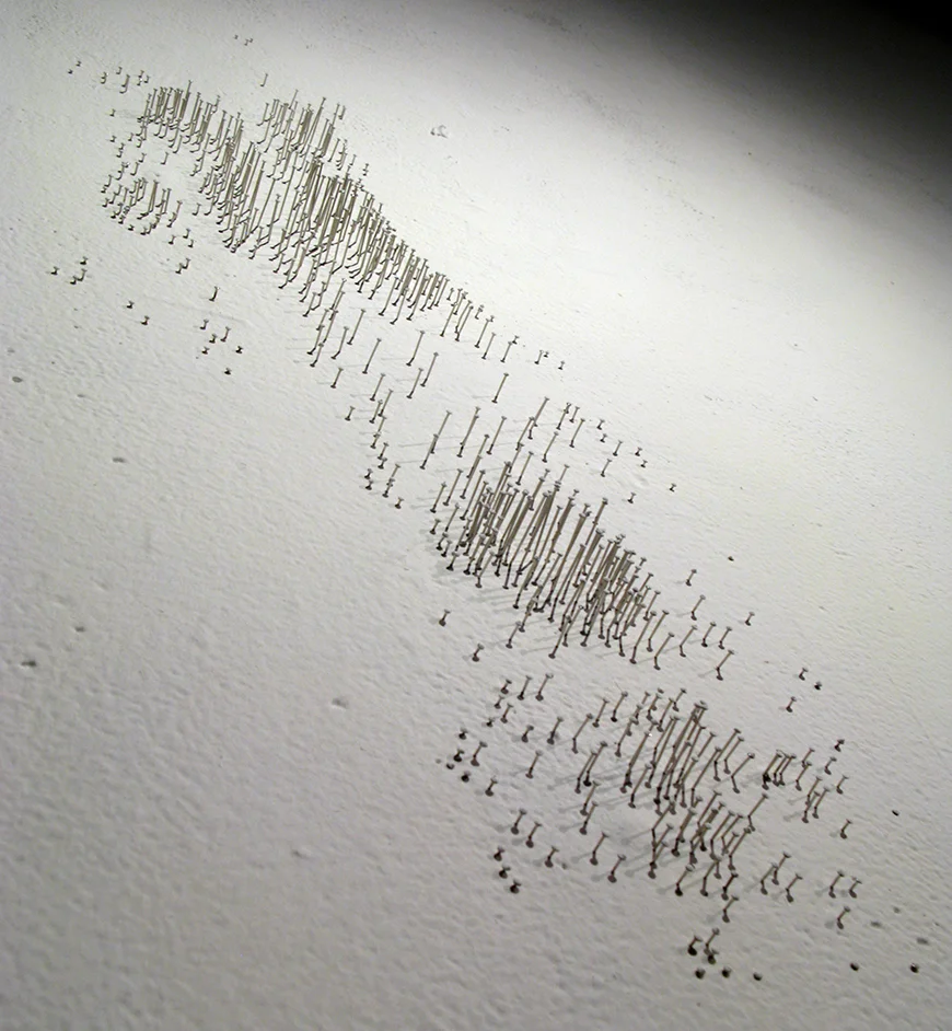 Yucca , 2011 steel pins and latex paint 22" x 8" A mountain-like landscape is created on the wall by mapping the location of each nuclear test that occurred on the flats of the nuclear testing range in Nevada. Each pin is painted to match the wall. Shadows paint the wall.