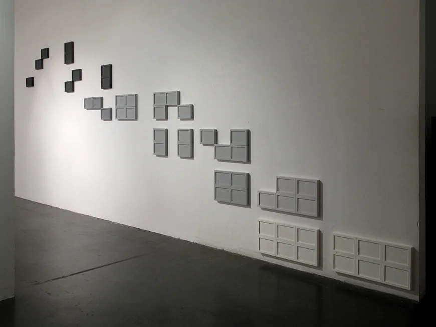 ...Nature of Things , 2011 hand-embossed paper, wood, acrylic spray paint dimensions variable At first glance, this work appears to be a random assortment of clustered rectangles. However, upon closer inspection the composition reveals itself to be a mere sliver of an invisible, symmetrical whole. Each individual frame contains a partial map of a symmetrical whole. The map subtly invites the viewer to understand their relationship to the invisible whole by virtue of being a witness to the missing information on each unique map. This system enables each version of the piece to adapt and respond to the site in which it is installed. A single cluster of frames provides enough information to understand the work.