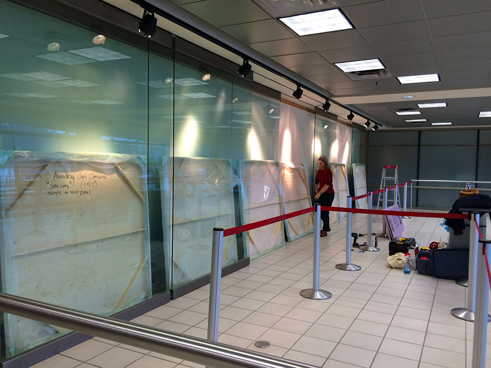 A complicated feat indeed when the hanging of a 35ft painting at Kelowna International Airport involves sliding seven, 5ft by 5ft wooden panels, laden with gobs of thick paint, behind narrow walls of glass. The glass wall panels hang from tracks in