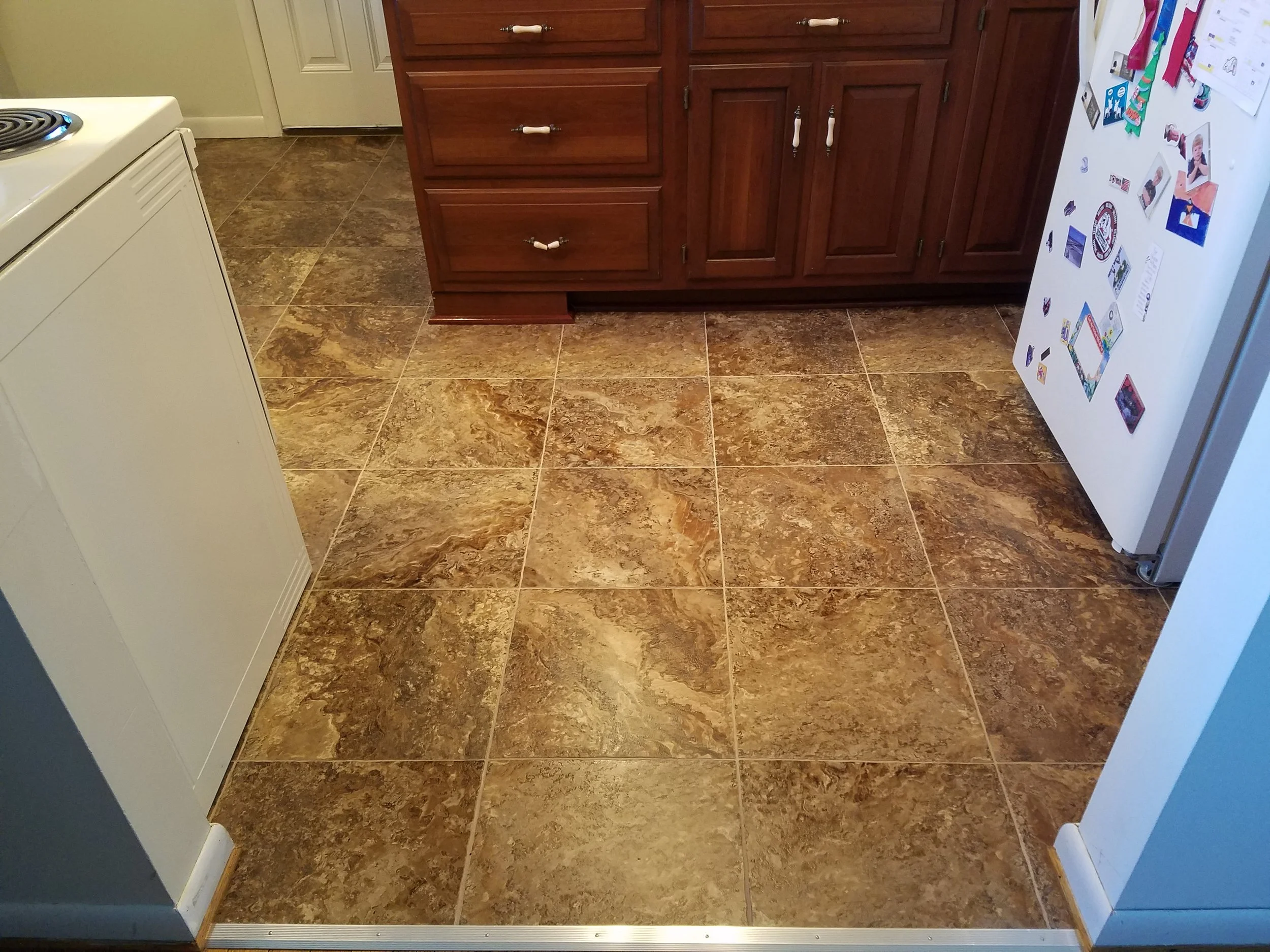 Armstrong luxury vinyl tile with grout installed in a kitchen. Vinyl tile gives the look of ceramic or porcelain tile but with a softer and warmer feel. Products such as this are also more budget friendly then standard tile. 