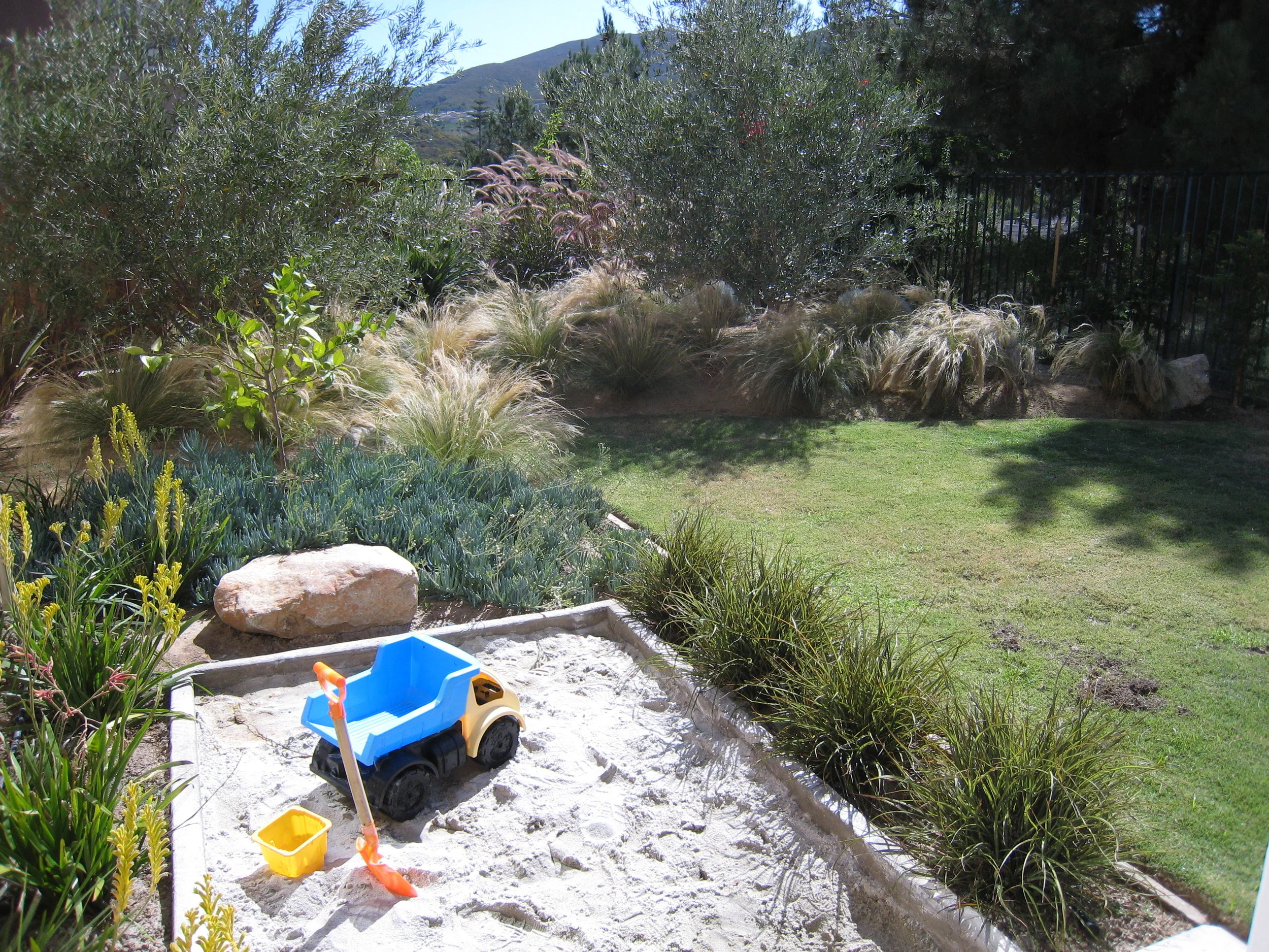 This sand box was easy to install and is not a total eye sore. The edges are blurred by grasses giving an appealing view for the adults but also creates an immersive experience for the children. No child wants to be out of site/out of mind, if possi…