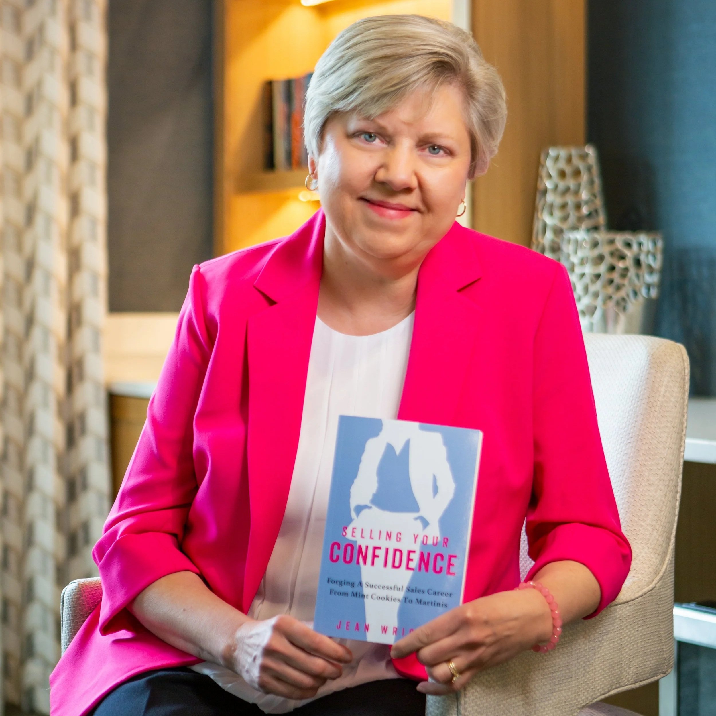 ce7c71c60eae2fd16c988b1b8db71fb6-JW-New Headshot pink w book (1).jpg