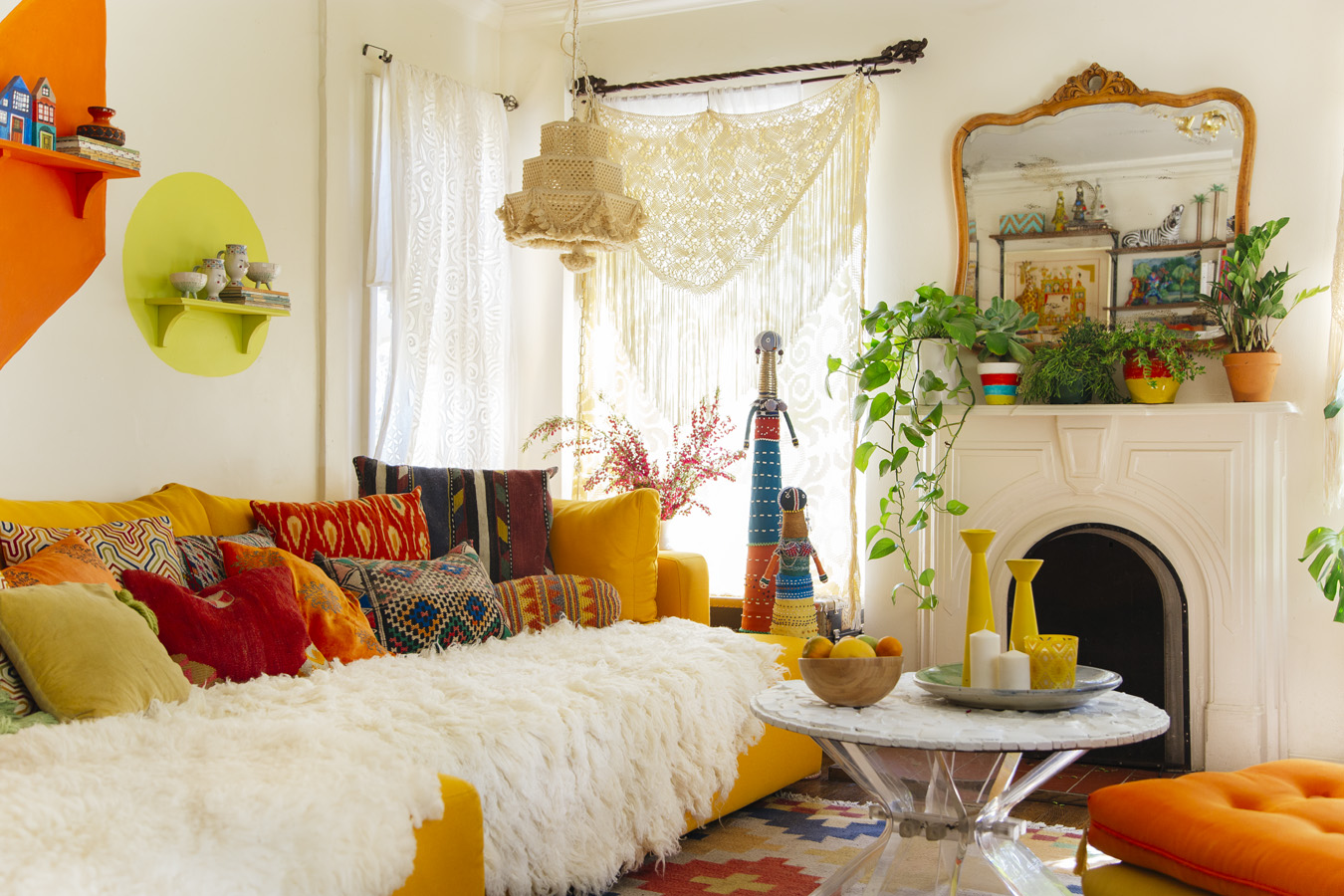 Photo from the book The New Bohemians: Cool and Collected Homes. A Living room with white walls, a bright yellow couch, white fur throw, and lots of yellow, orange, and lime green accessories