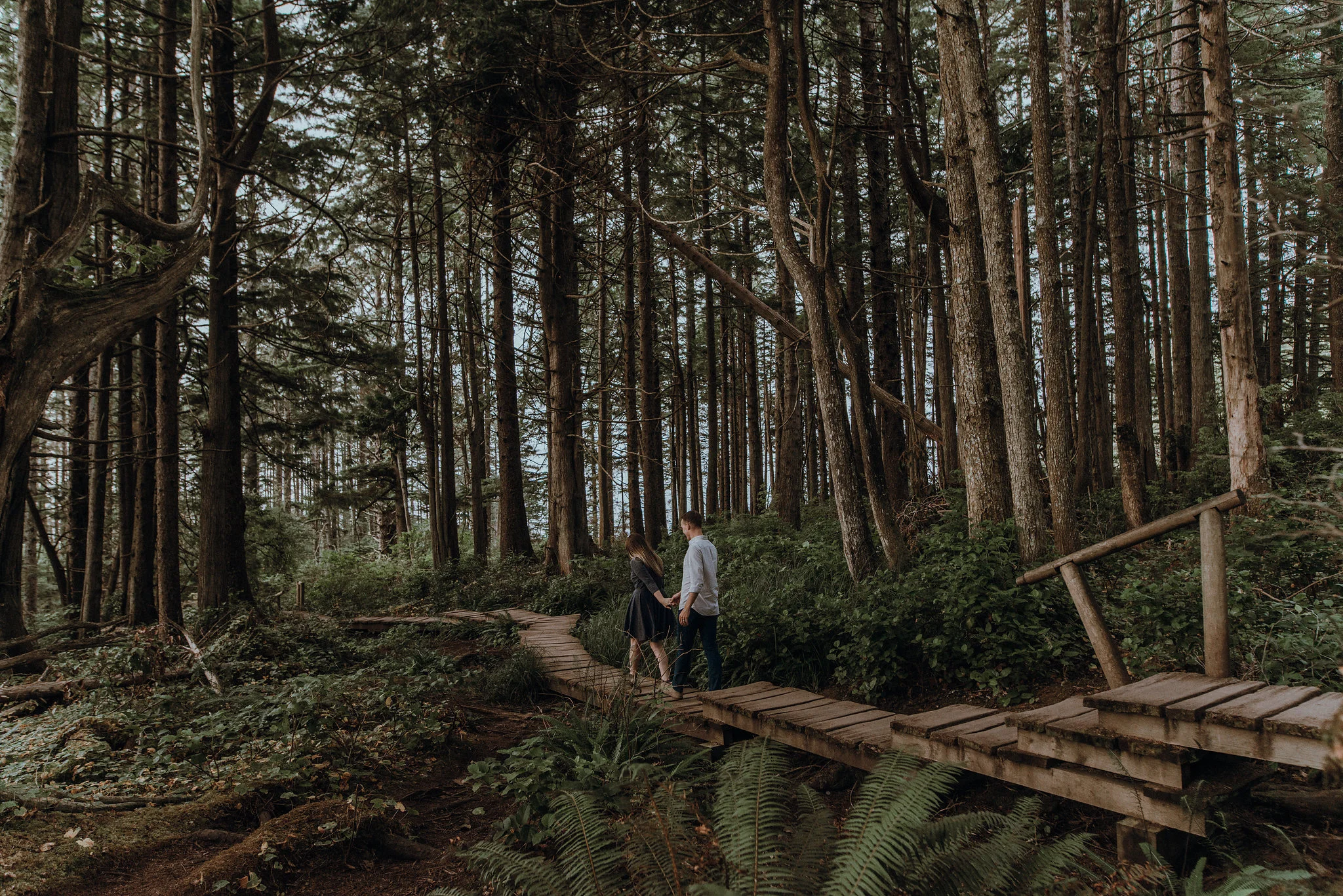 Pacific Northwest couple holding hands at engagement session and walking through forest. 
