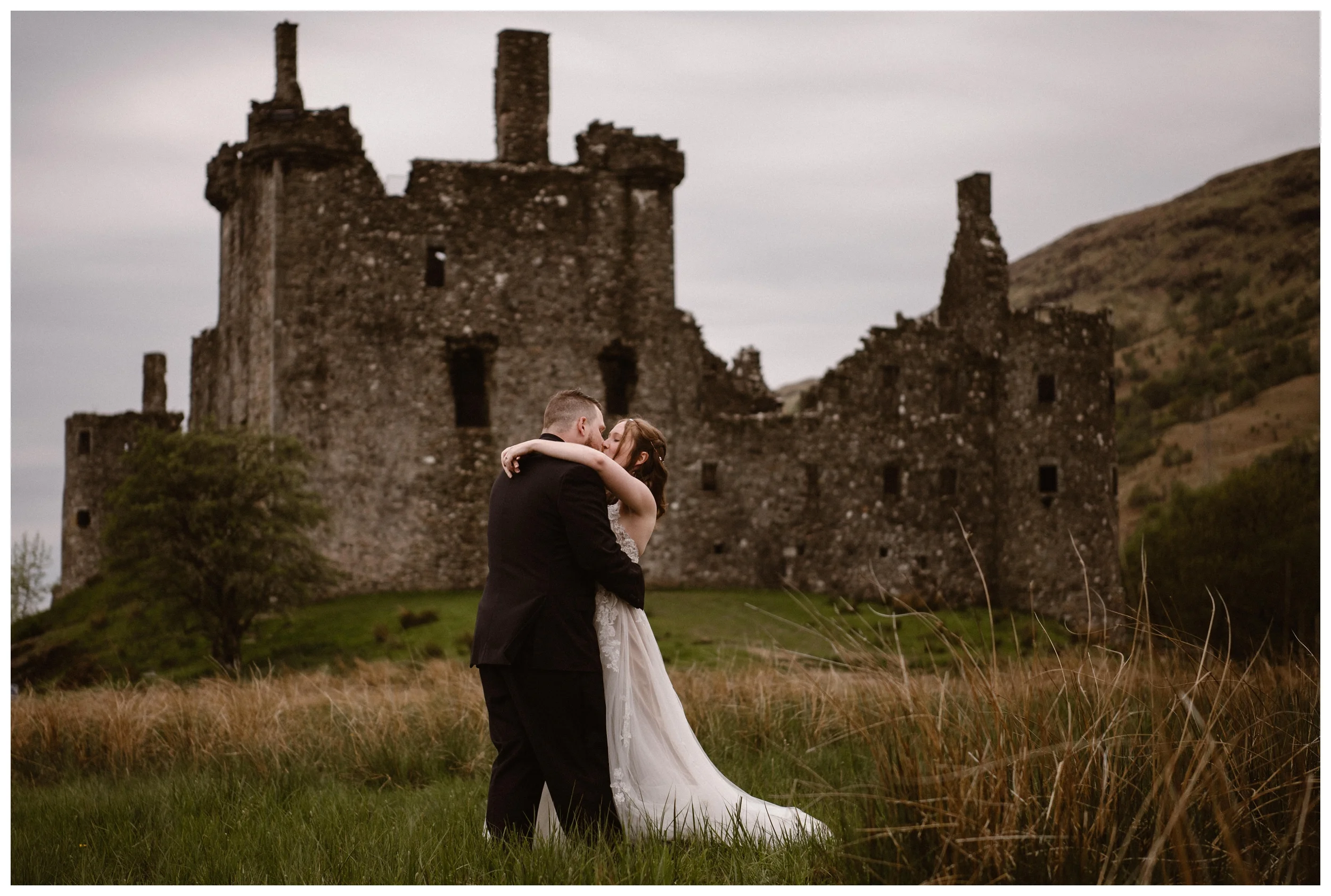 Daniel and Elissa share a kiss during their first look outside the ruins of Kilchurn Castle in Lochawe in the Scottish Highlands. Photo by Maddie Mae, Adventure Instead.