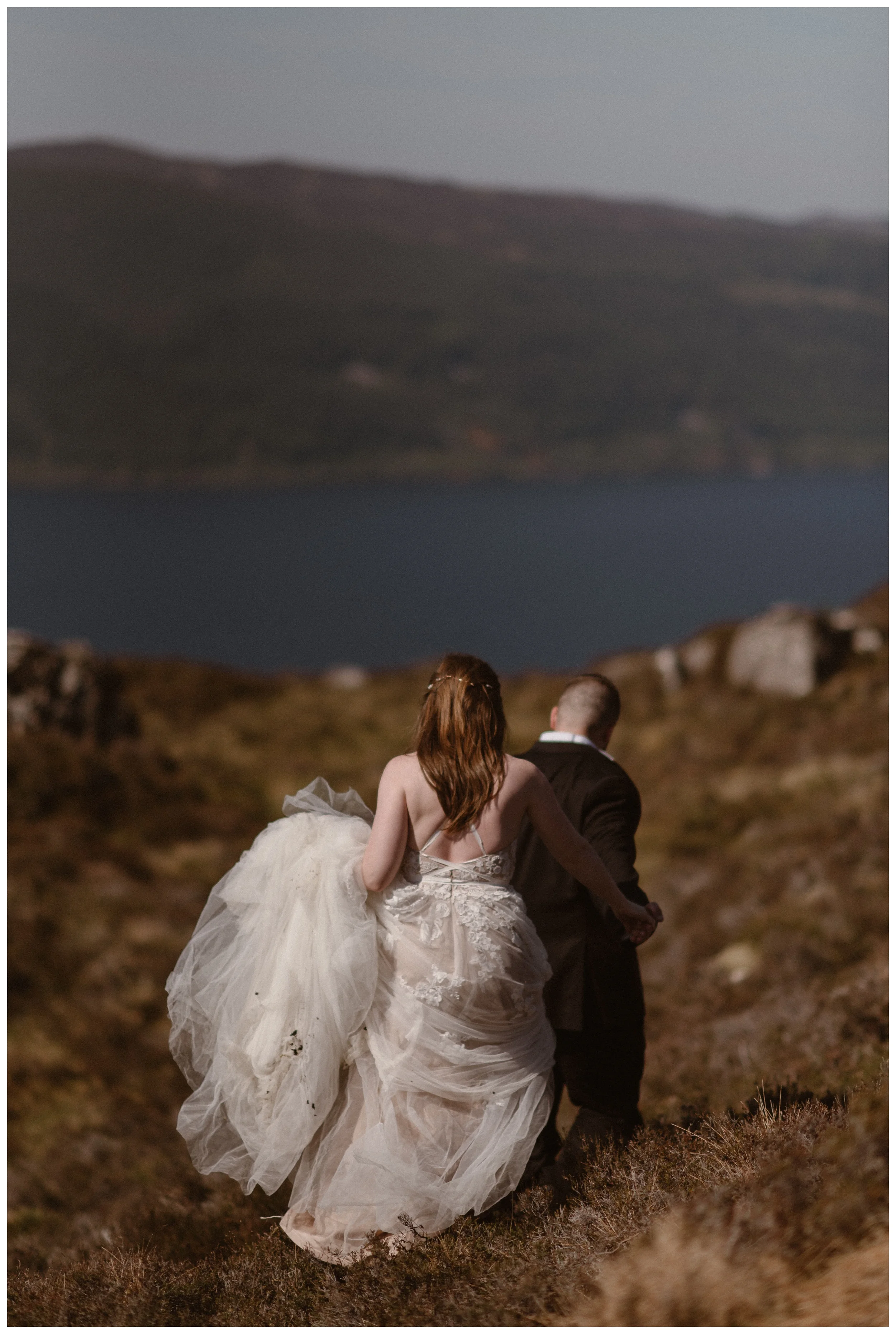 Elissa and Daniel hiked, wandered, and explored the shores of Loch ness in the Scottish Highlands in their wedding day attire following their Glencoe, Scotland elopement. Photo by Maddie Mae, Adventure Instead.
