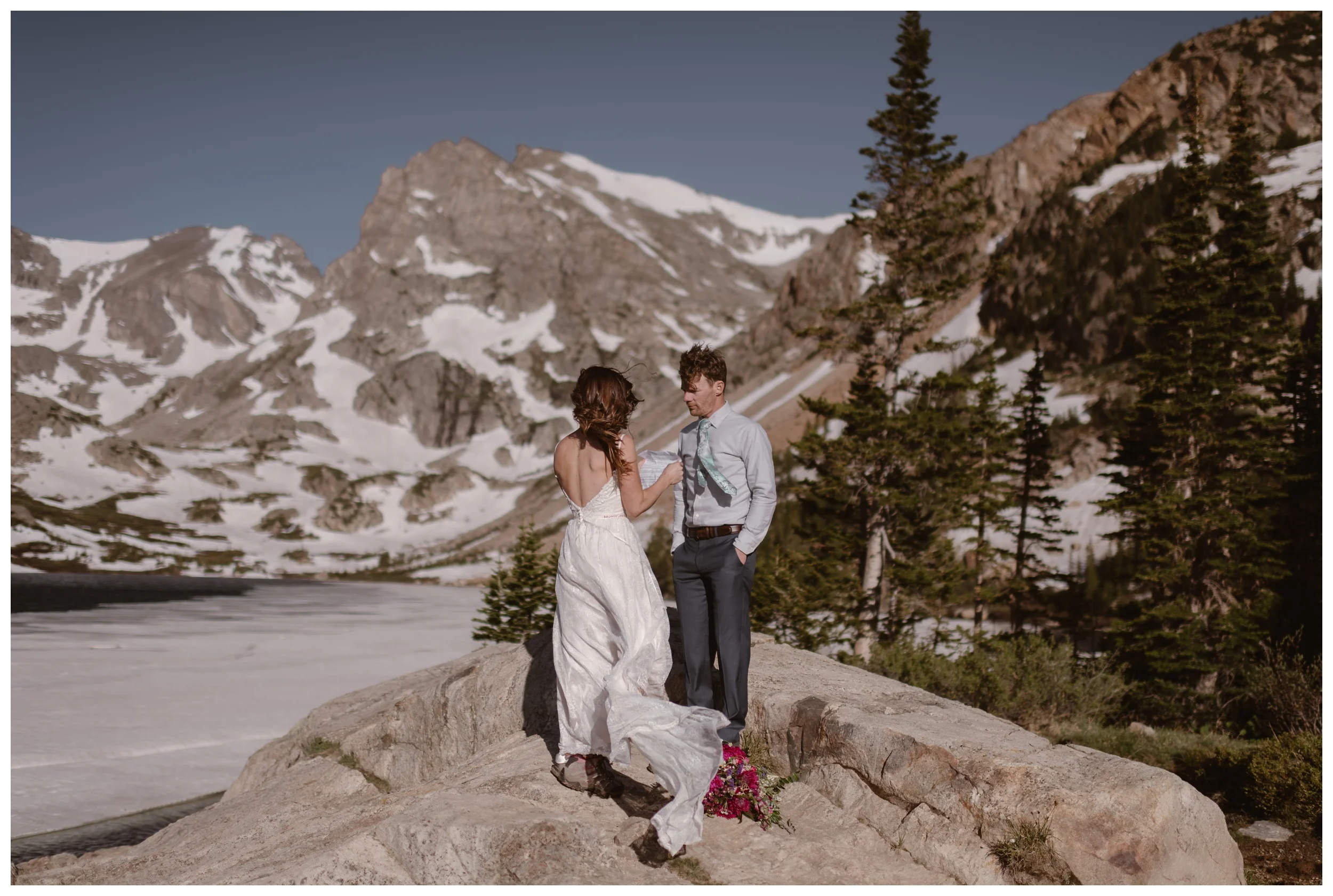 As the high alpine wind blows around them, Karen and Matt read their vows during their adventure elopement ceremony at the top of Lake Isabelle, above Brainard Lake in Nederland, Colorado. Photo by Adventure Instead, Maddie Mae.