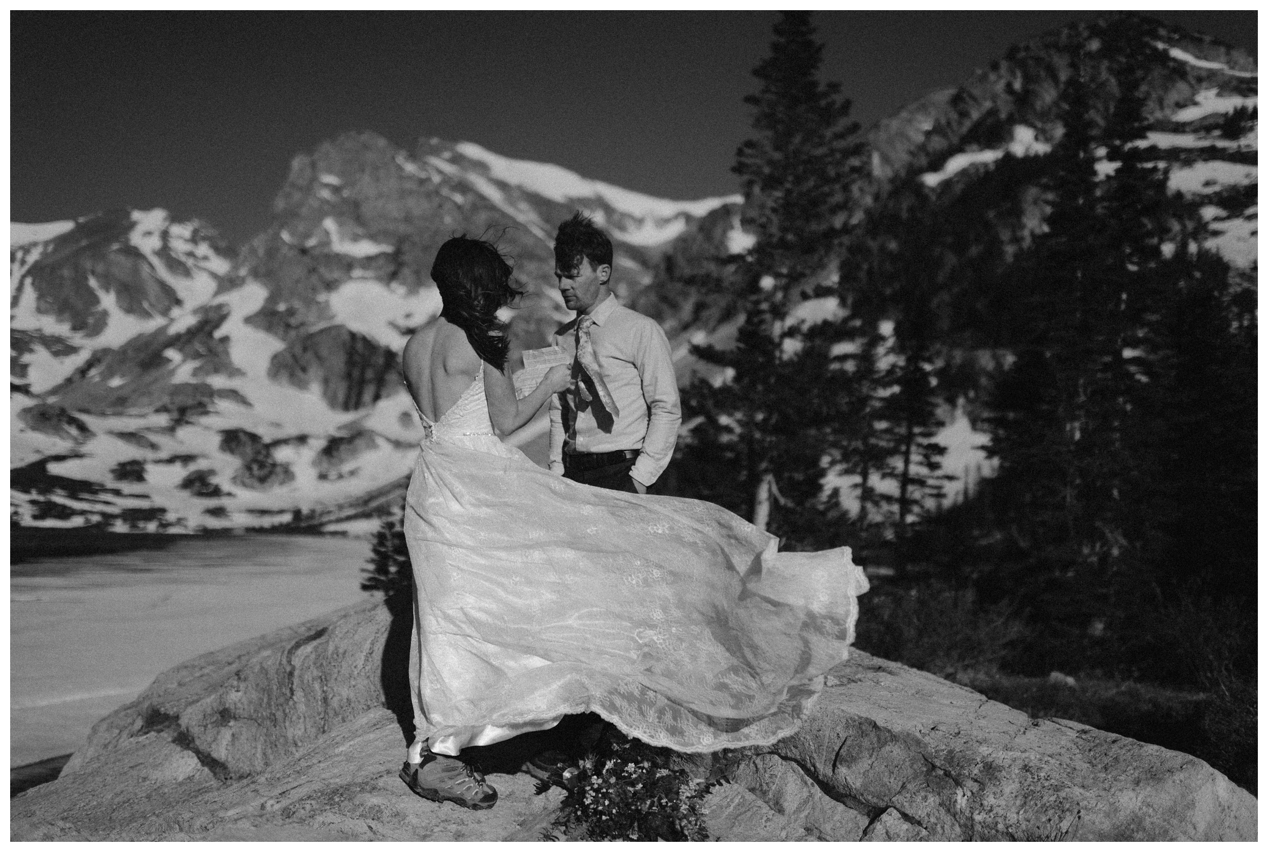 Karen’s dress blows as she reads her vows during their self solemnizing elopement wedding ceremony at the top of Lake Isabelle in Nederland, Colorado. Photo by Adventure Instead, Maddie Mae.