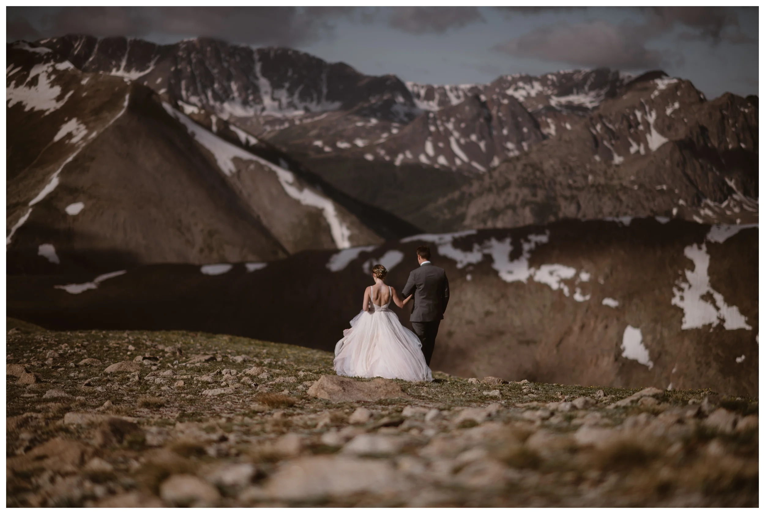 Stunningly jagged peaks lit by the rising sun loom before Marcela and Vasily as they walk away from their hiking elopement ceremony on the top of Independence Pass. Photo by Maddie Mae, Adventure Instead.